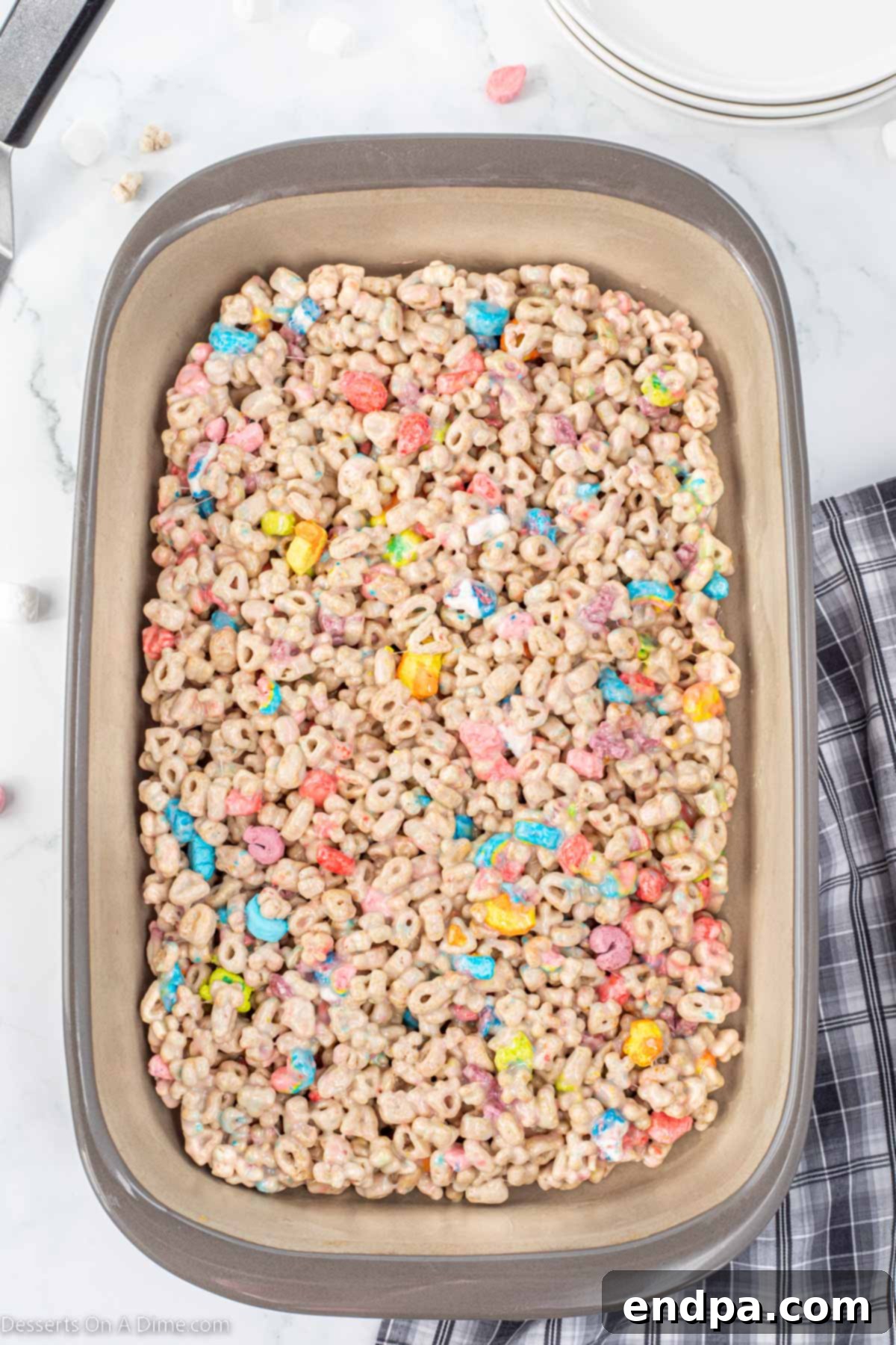 The Lucky Charm Treat mixture spread evenly into a 9x13 inch baking pan, ready for cooling.