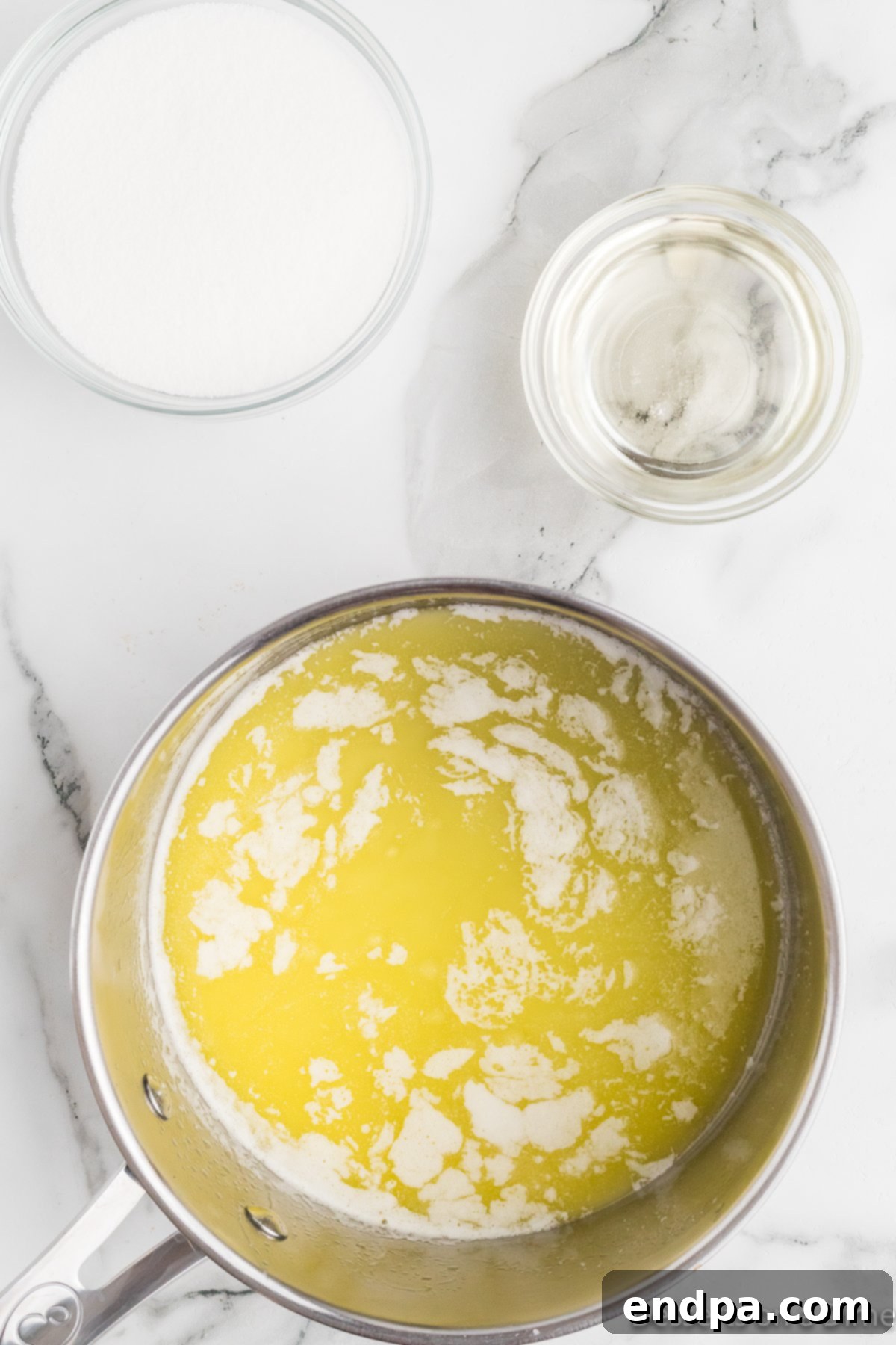 Rainbow Jello Popcorn Delight 4 Melted butter in saucepan. A medium-sized saucepan on a stovetop contains golden, melted butter, gently simmering over low heat. The warm, inviting color suggests the start of a sweet and flavorful mixture.