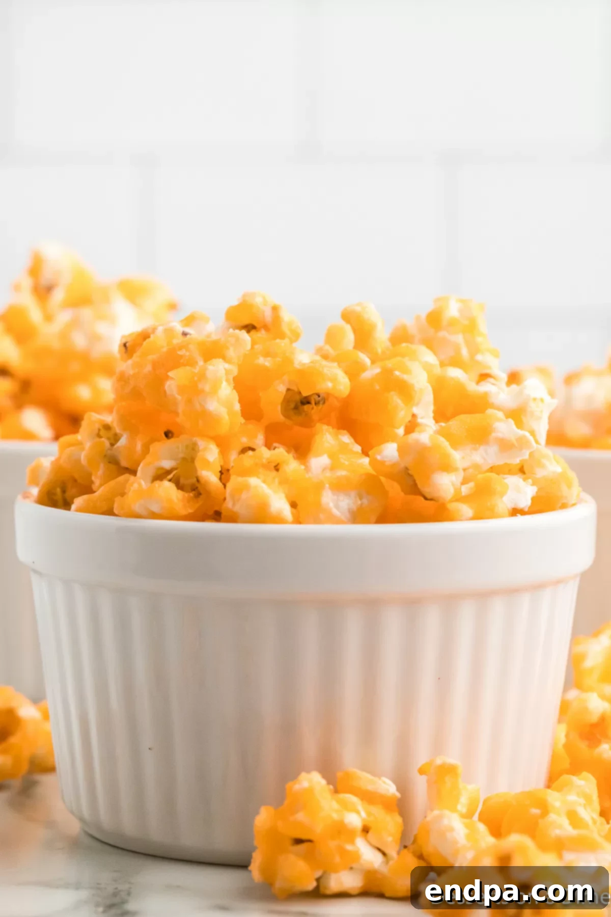 Rainbow Jello Popcorn Delight 7 Jello Popcorn in a bowl. A close-up shot of vibrant red Jello popcorn filling a white bowl, ready to be served. Each piece is perfectly coated and glistening, highlighting its appealing texture and festive color.