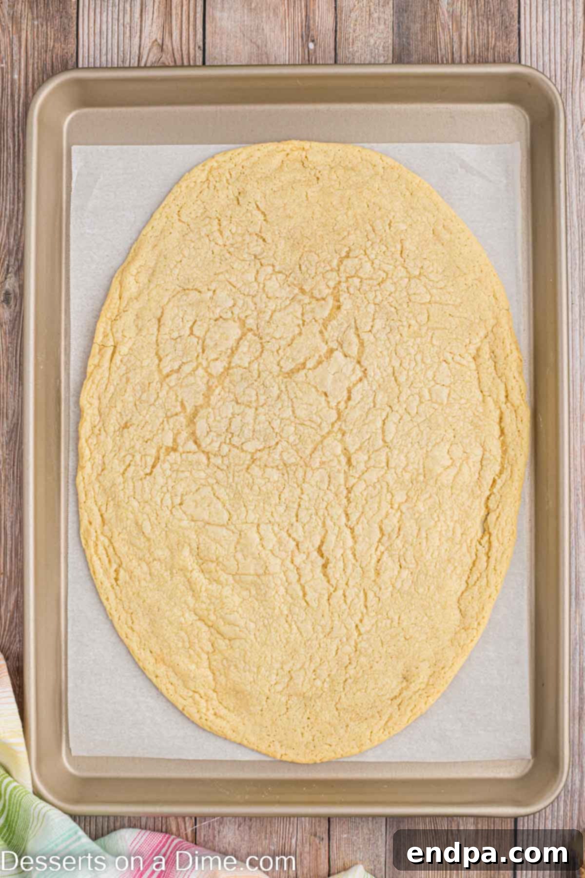 Sugar cookie dough rolled out into an oval, egg-like shape on a parchment paper-lined baking sheet, ready for the oven.
