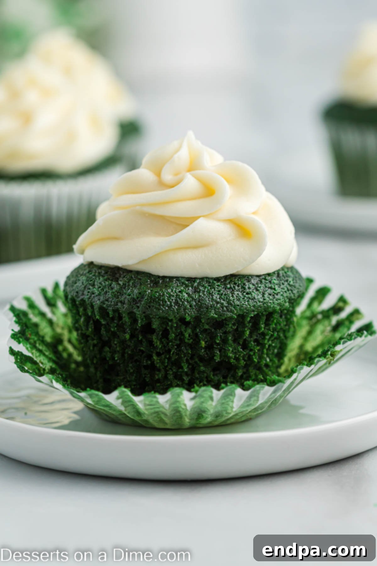 A beautifully frosted green velvet cupcake on a pristine white platter, garnished with festive sprinkles.
