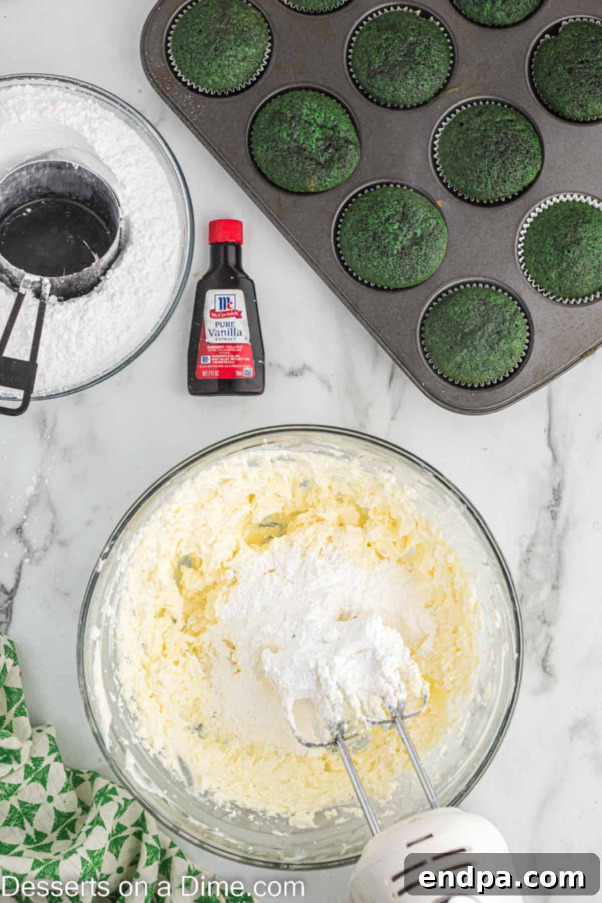 Powdered sugar being slowly incorporated into the cream cheese and butter mixture for frosting.