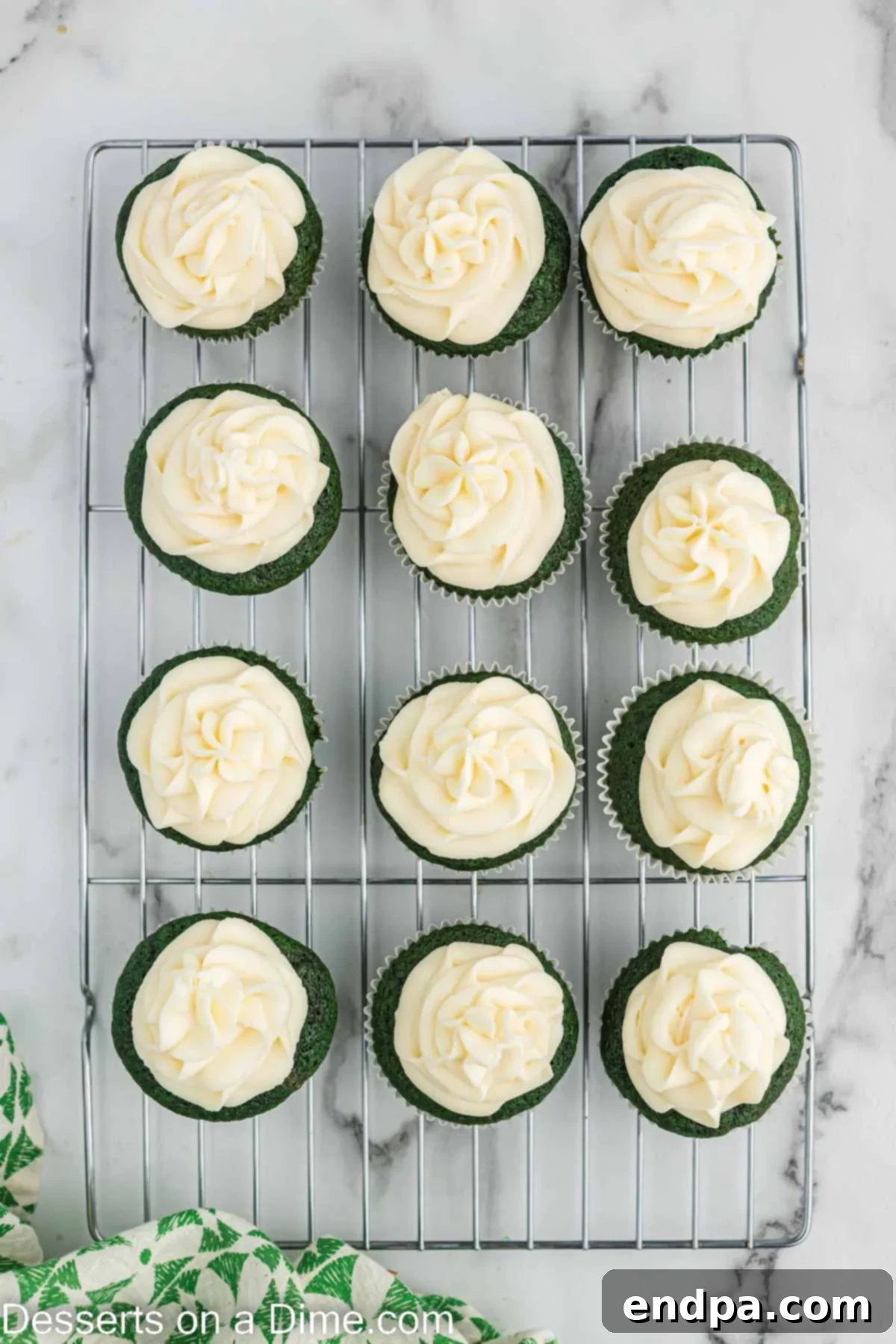 A close-up shot of a green velvet cupcake perfectly frosted with creamy white cream cheese frosting.