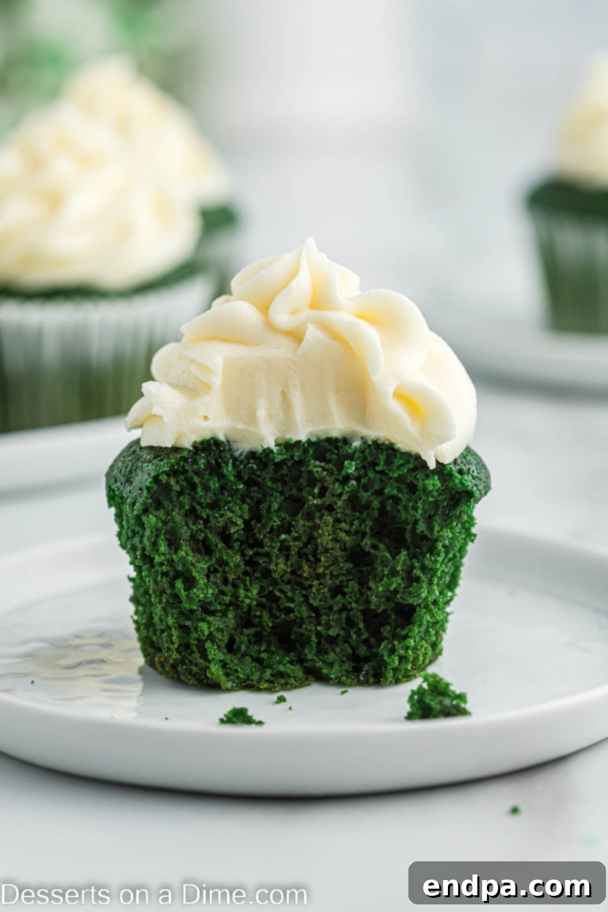 A single green velvet cupcake with a swirl of cream cheese frosting sits on a delicate plate, ready to be enjoyed.