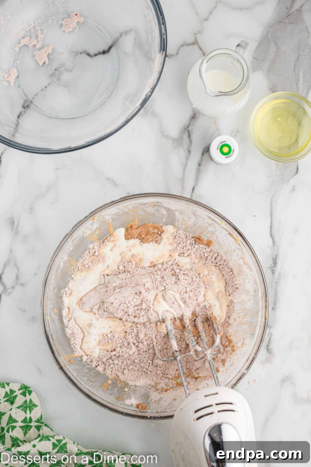 Vegetable oil, egg yolks, and vanilla extract being added to the creamed butter and sugar mixture.