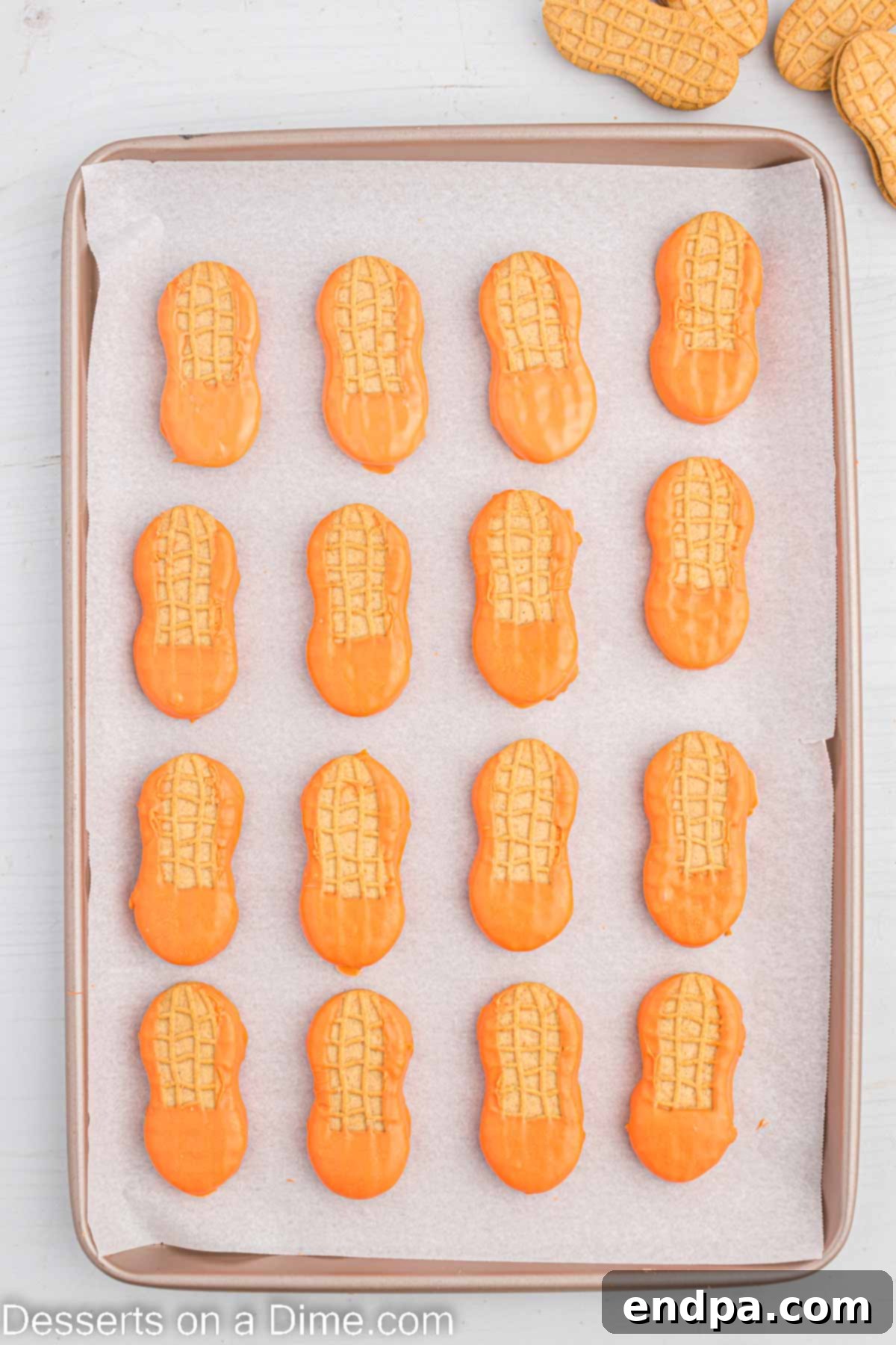 Lucky Leprechaun Bites 5 Row of orange-dipped Nutter Butter cookies, forming leprechaun faces and beards, cooling on parchment paper.