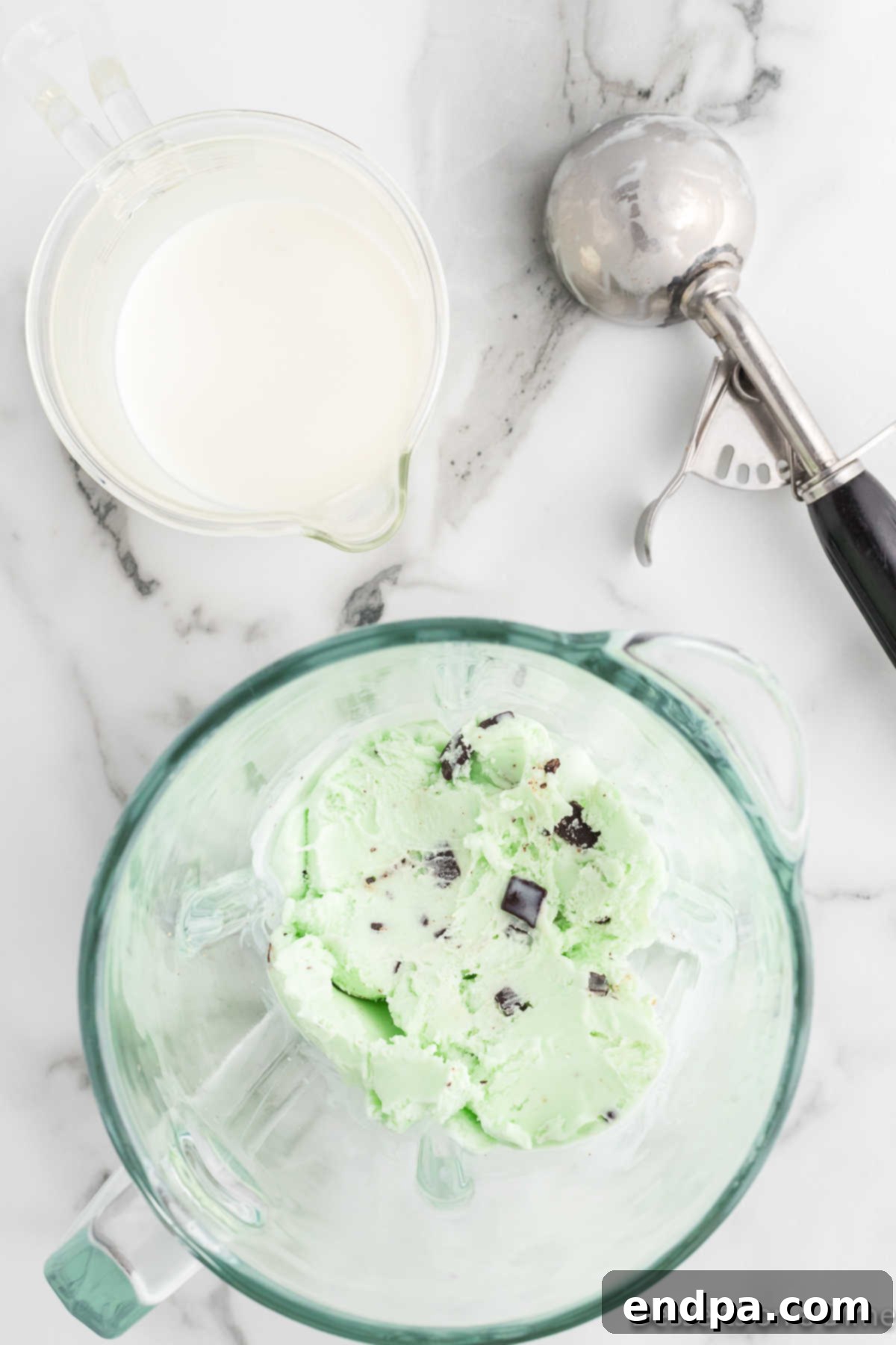 A blender jar filled with scoops of mint chocolate chip ice cream, ready for blending.