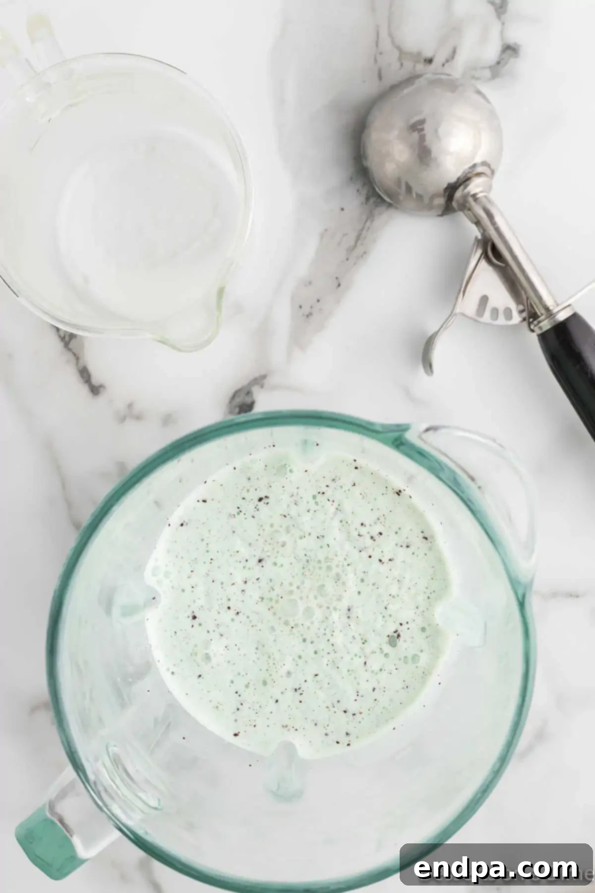 The ice cream and milk are blended into a smooth, thick green mixture inside the blender jar.