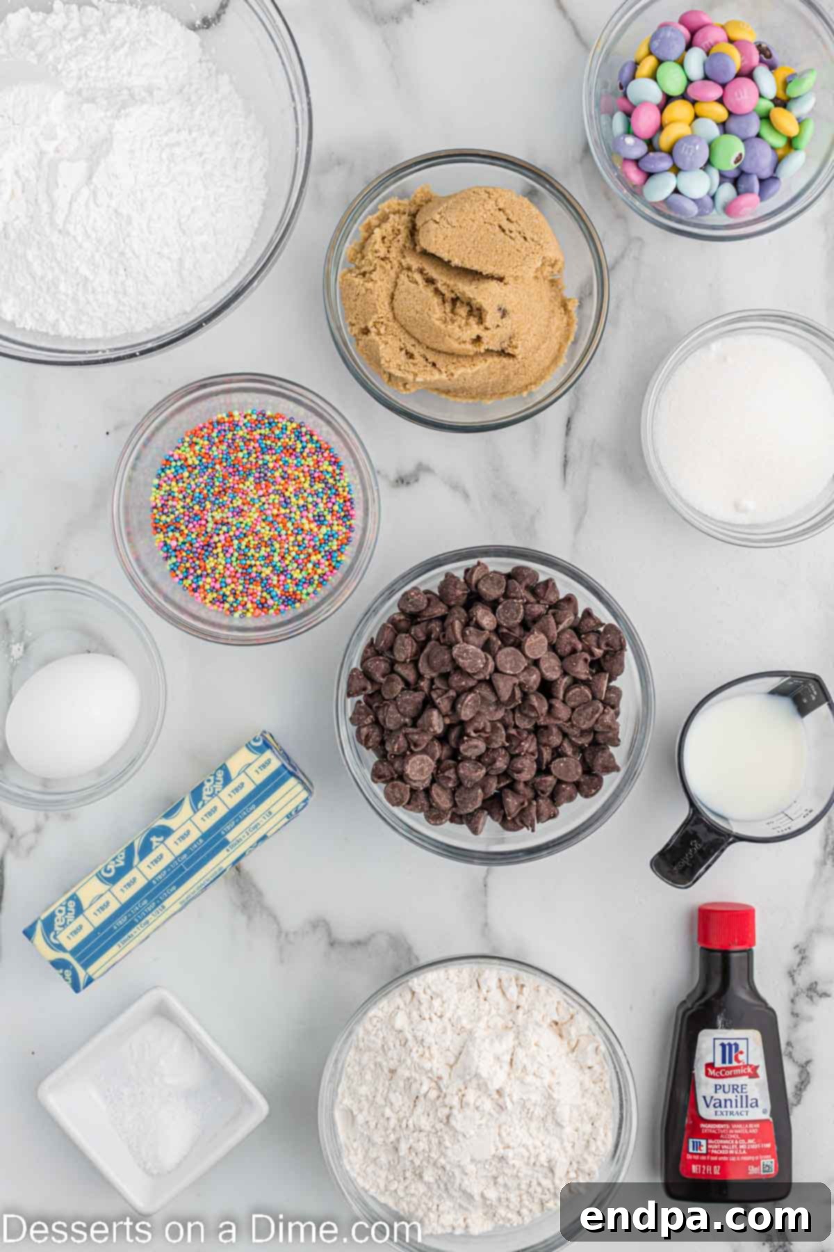 Ingredients needed for Easter Cookie Cake - butter, brown sugar, sugar, egg, vanilla, flour, baking soda, salt, chocolate chips, M&M's, sprinkles, powdered sugar, milk neatly arranged
