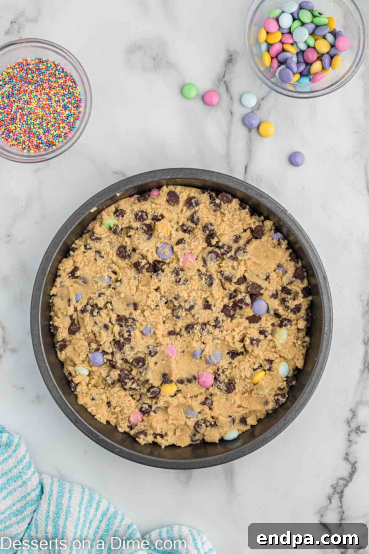 Cookie dough pressed evenly into a round cake pan, ready for baking