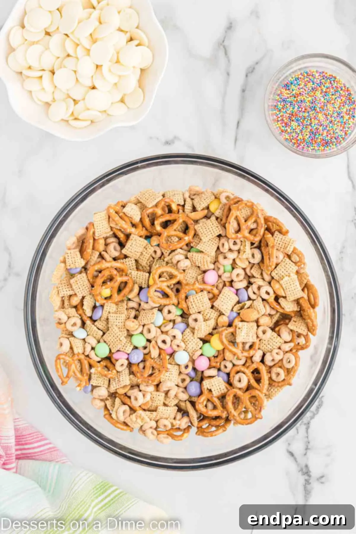 Bunny Magnet Mix 4 Large mixing bowl with dry ingredients: Chex cereal, Honey Nut Cheerios, pretzels, peanuts, and pastel M&M's, ready for mixing.