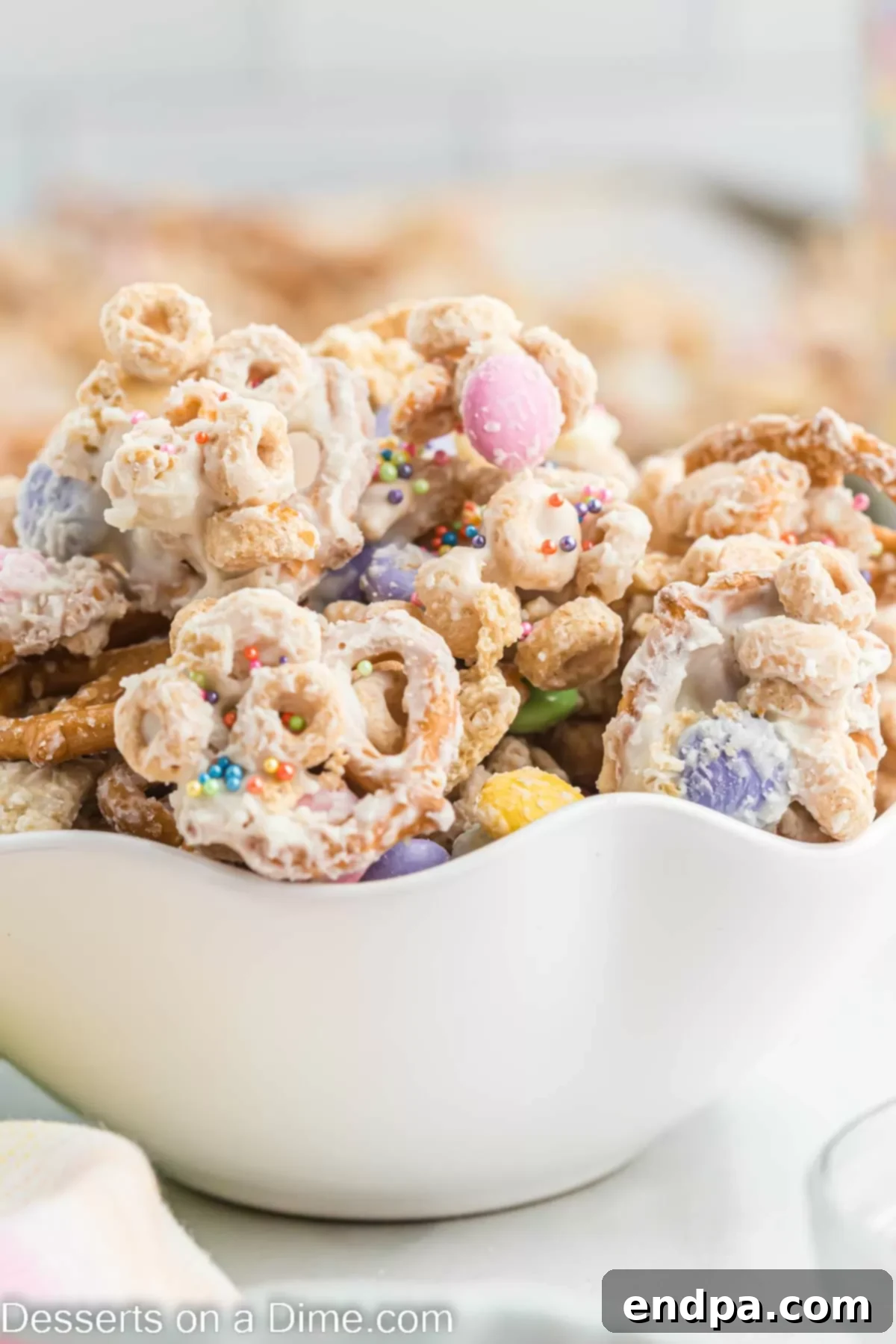Bunny Magnet Mix 9 A close-up shot of Easter Bunny Bait in a bowl, highlighting the textures and colors of the white chocolate-coated pretzels, cereal, M&M's, and sprinkles.
