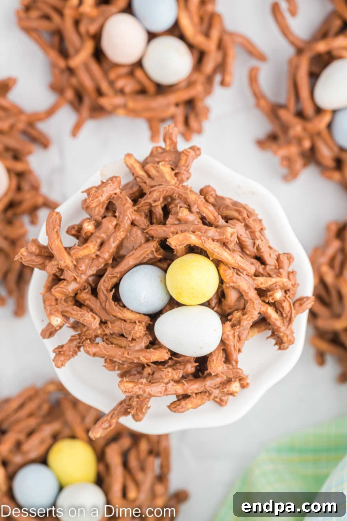Colorful candy eggs placed into the center of chocolate bird's nests on a baking sheet.
