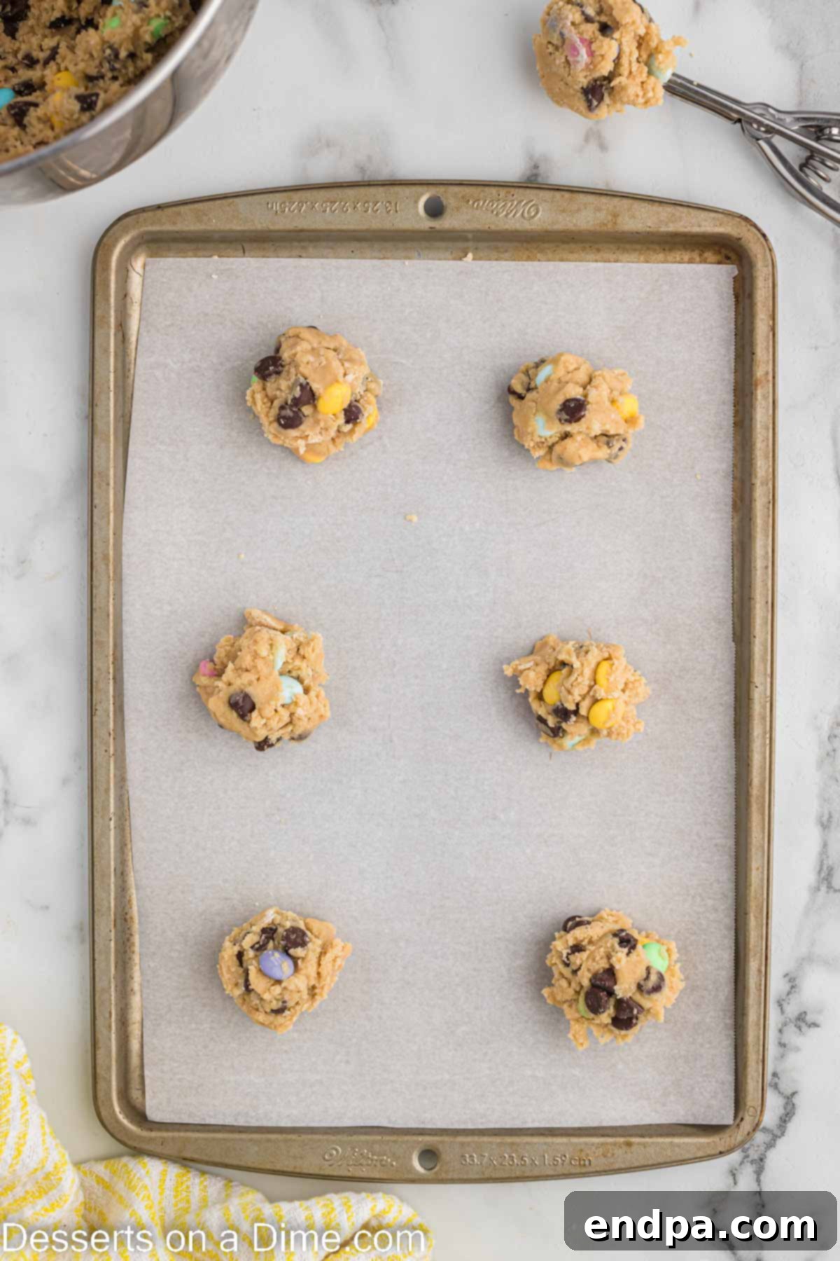 Hoppy Easter Chocolate Chip Cookies 7 Portioned cookie dough balls, topped with reserved Easter M&M's, neatly arranged on a baking sheet.