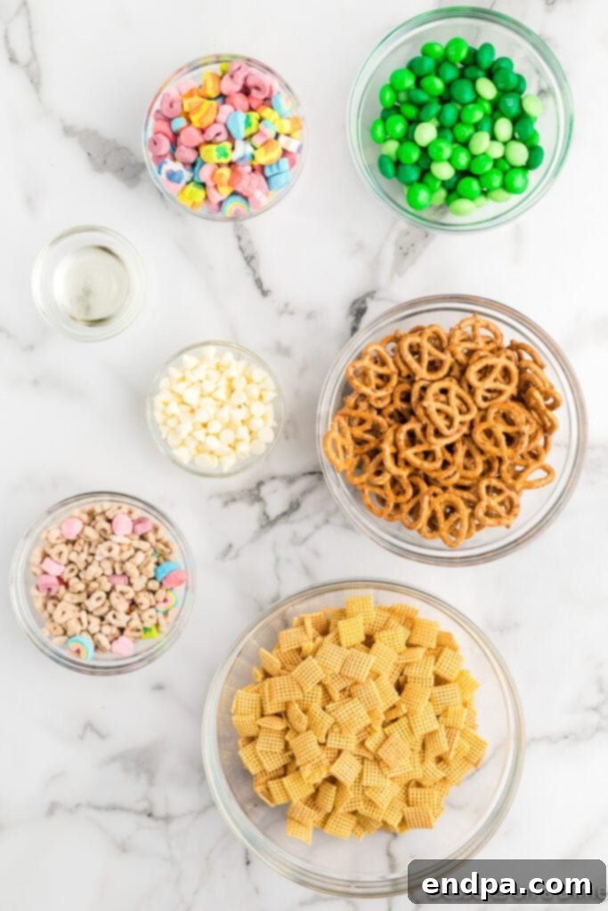 The Leprechaun's Lure 3 Ingredients for Leprechaun bait laid out: pretzels, Lucky Charms cereal, Chex cereal, M&Ms, and white baking chips.