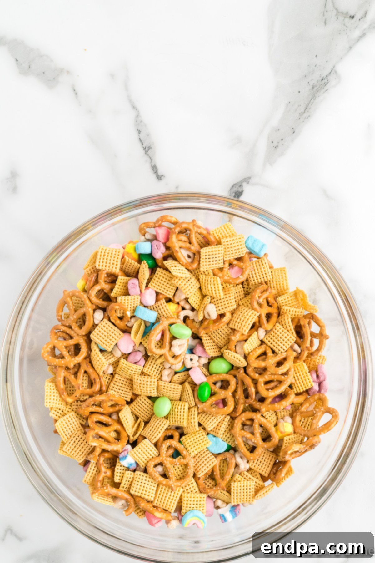 The Leprechaun's Lure 4 A large bowl filled with a mixture of Chex cereal, Lucky Charms, marshmallows, and pretzels, ready to be coated.