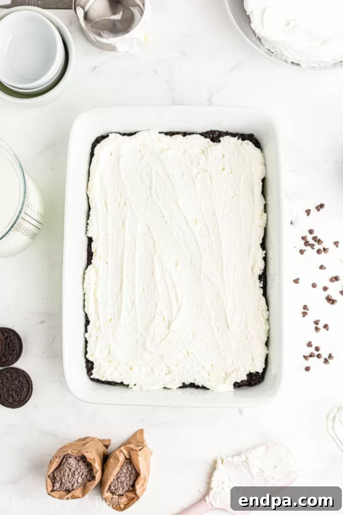 Whipped cream spread on top of layers in baking dish. 