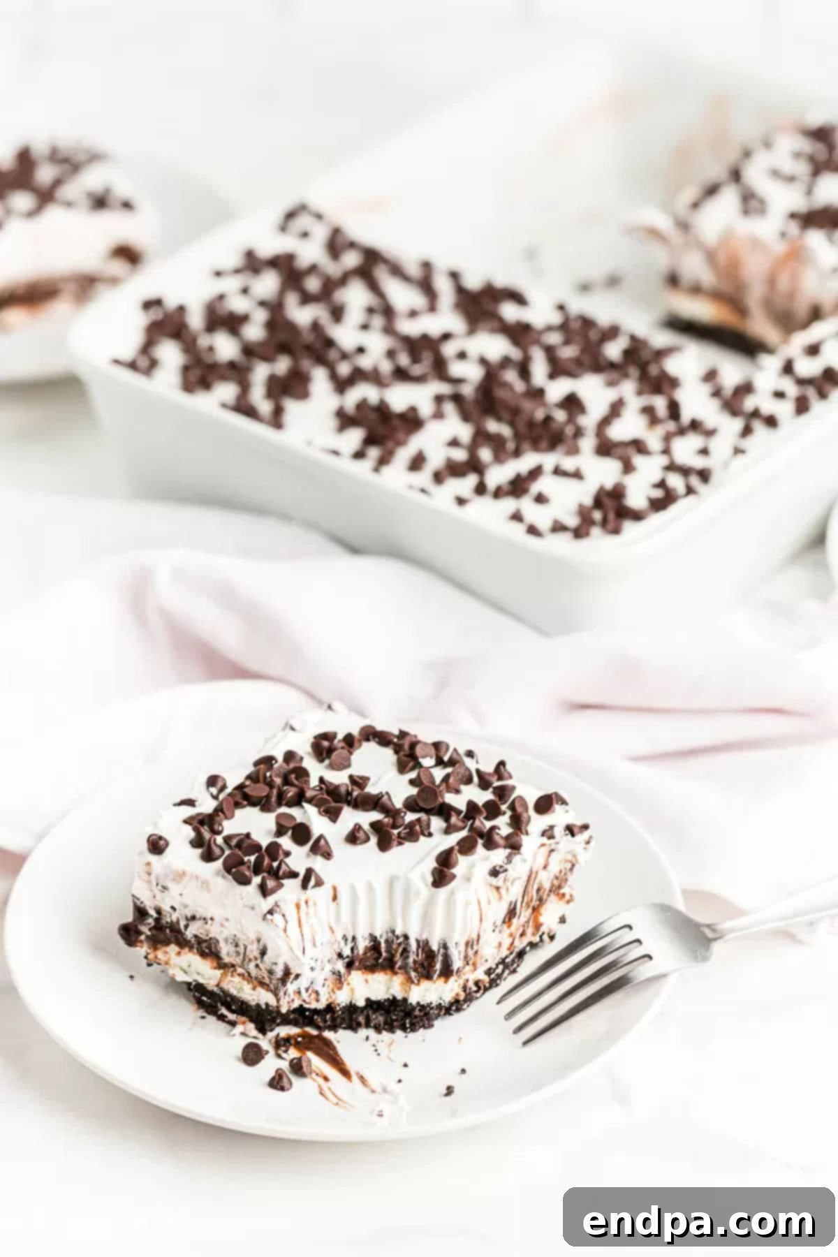 a square piece of chocolate lasagna on a plate with a fork. 