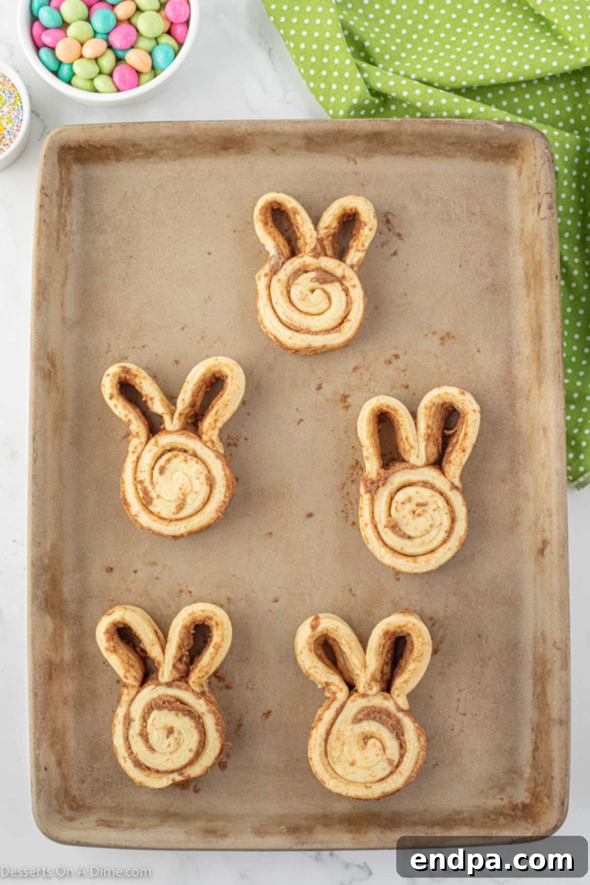 Cinnamon rolls shaped into bunnies on a baking sheet before baking.