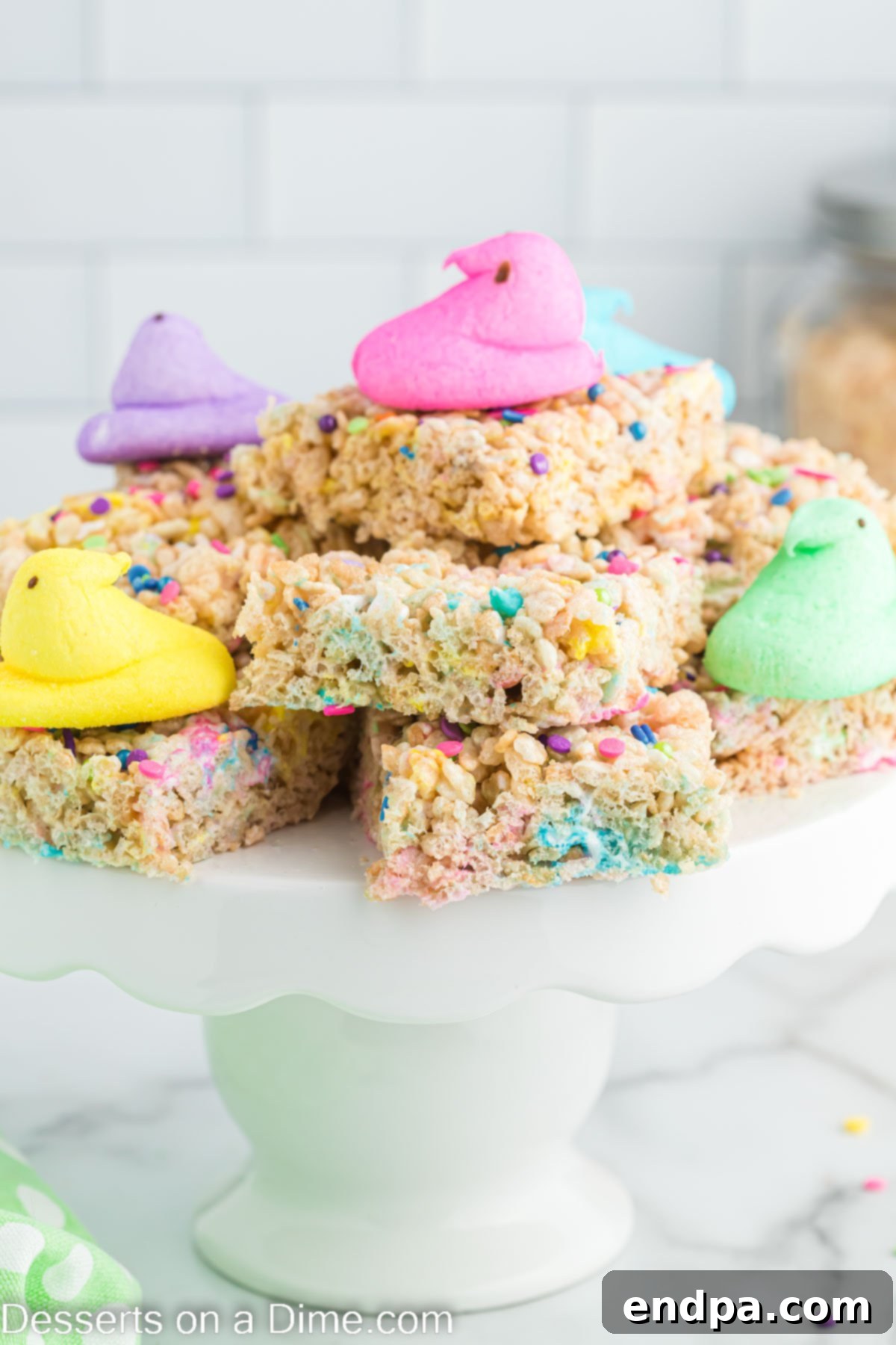 Peeps Rice Krispie Treats stacked on a platter with peeps on top, showcasing their vibrant colors and gooey texture.