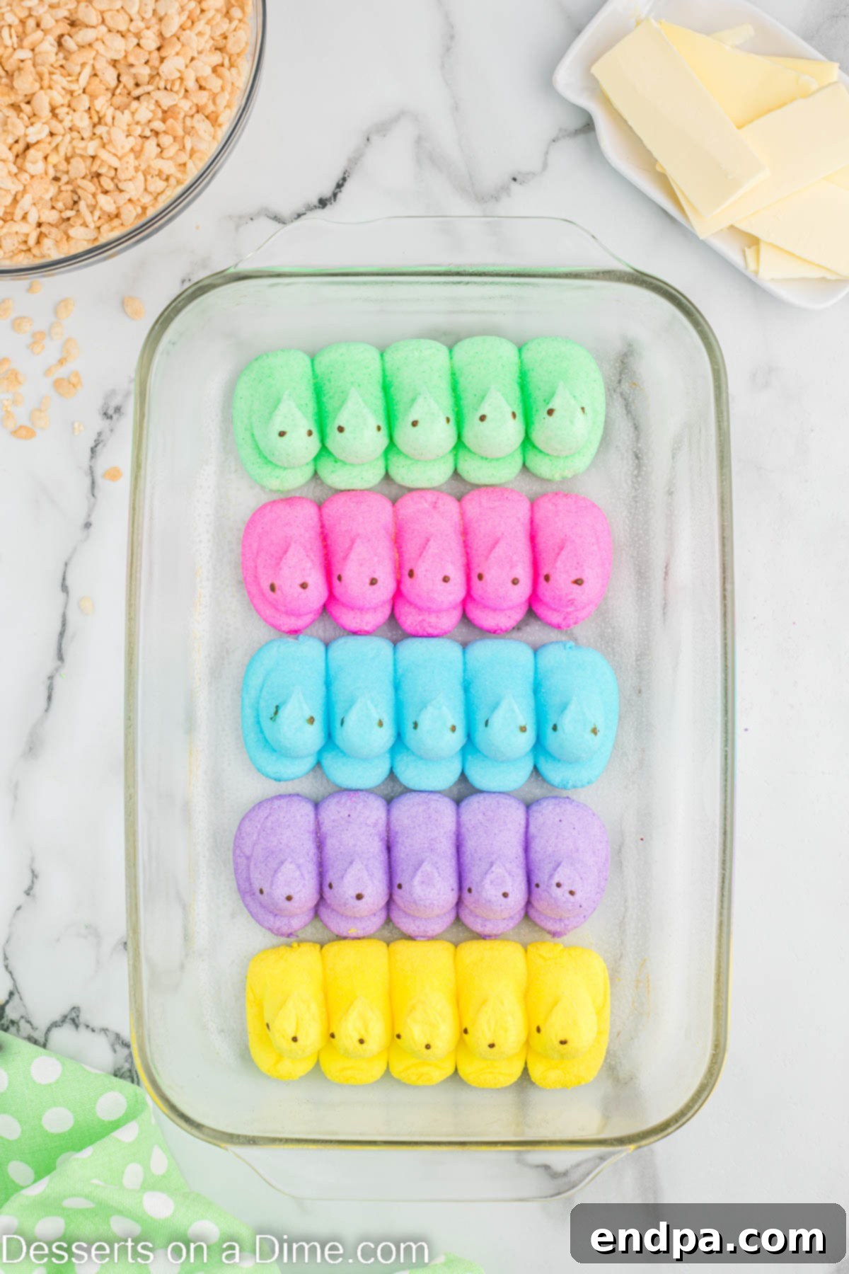 Pink, blue, and yellow Peeps arranged in a single layer in the bottom of a baking dish.