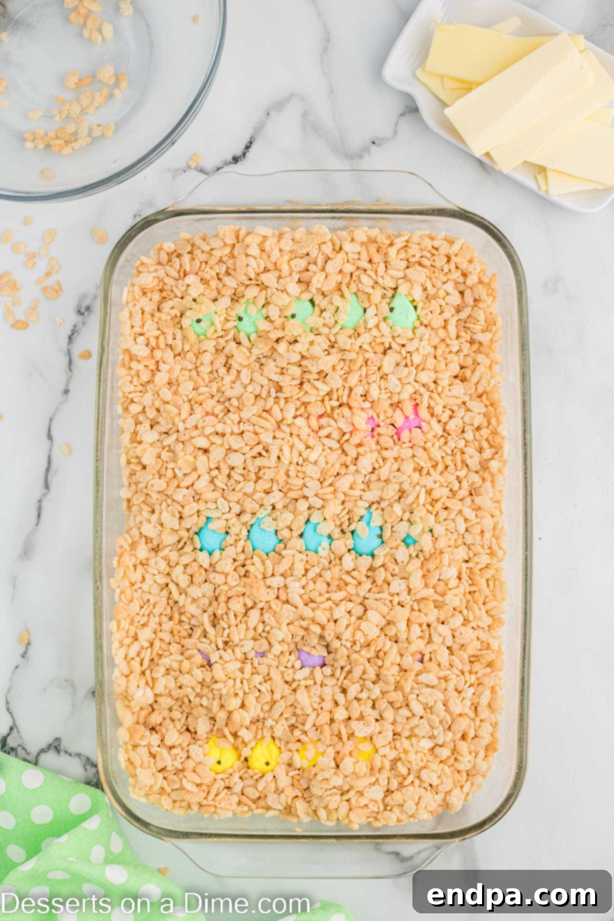 Rice Krispie Cereal poured evenly over the layer of Peeps in the baking dish.