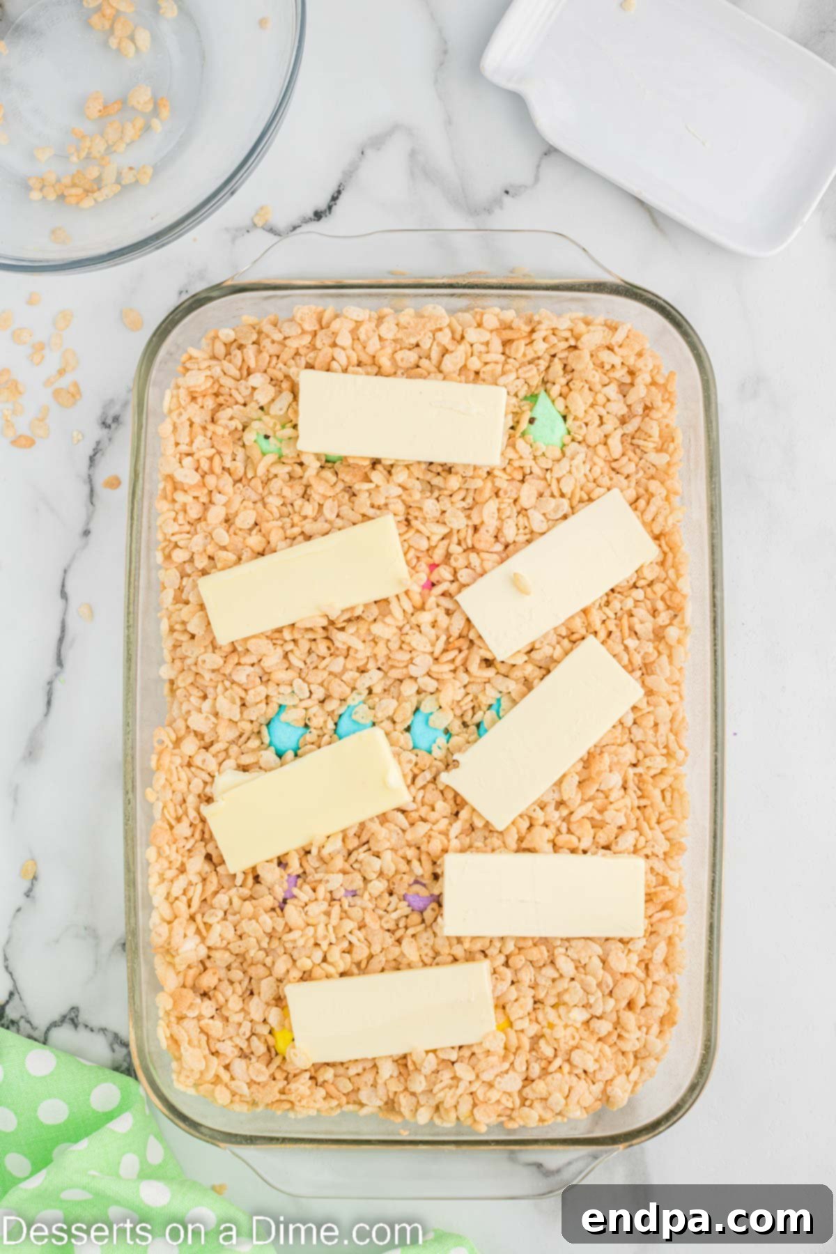 Thin strips of butter arranged on top of the cereal layer in the baking dish.