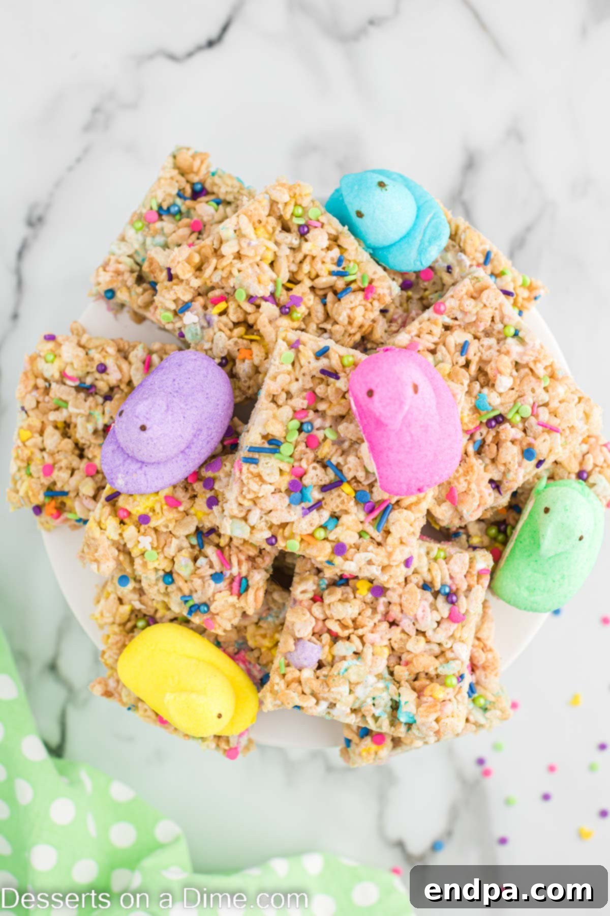 Peeps Rice Krispie Treats stacked on a platter with Peeps on top, ready to be served.