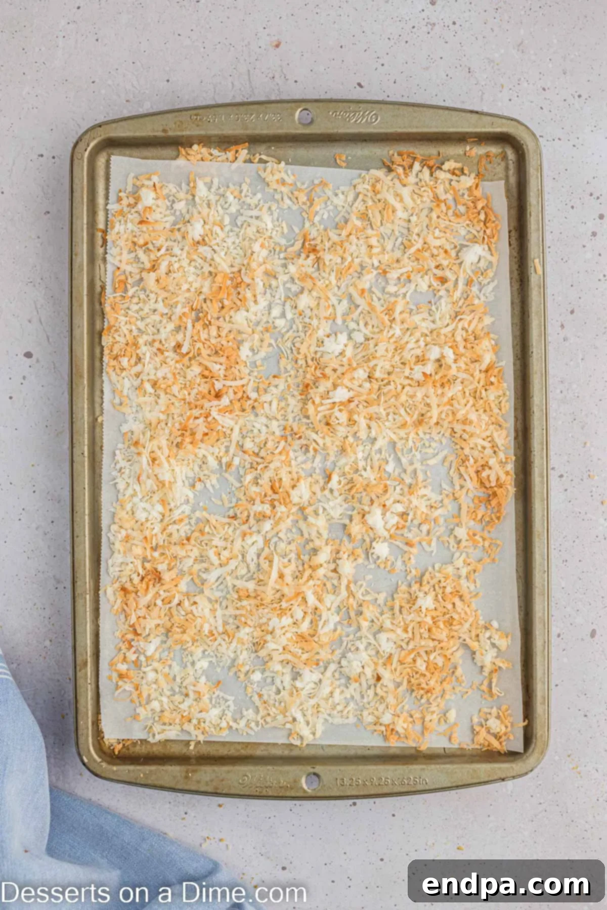 Hoppy Easter Cheesecake Bites 9 Shredded coconut spread on a parchment-lined baking sheet, freshly toasted to a golden brown.