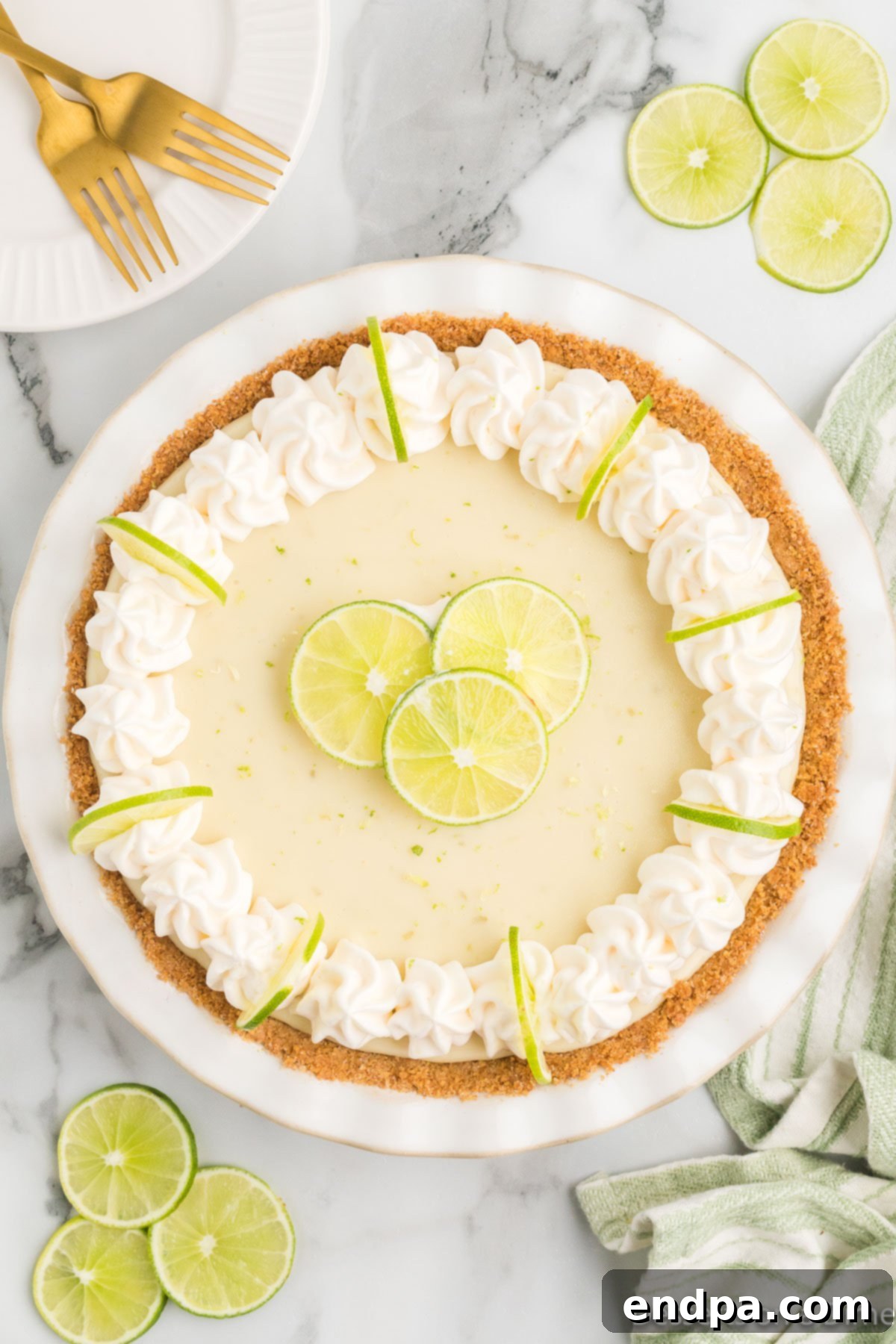 Foolproof Tangy Key Lime Pie 9 Pie topped with whipped cream and lime slices.