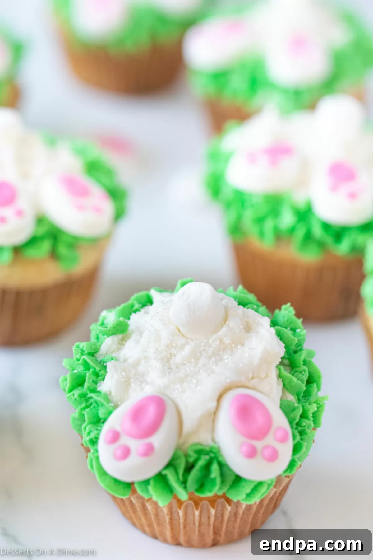 Mini marshmallow tails and bunny feet added to decorated cupcakes.