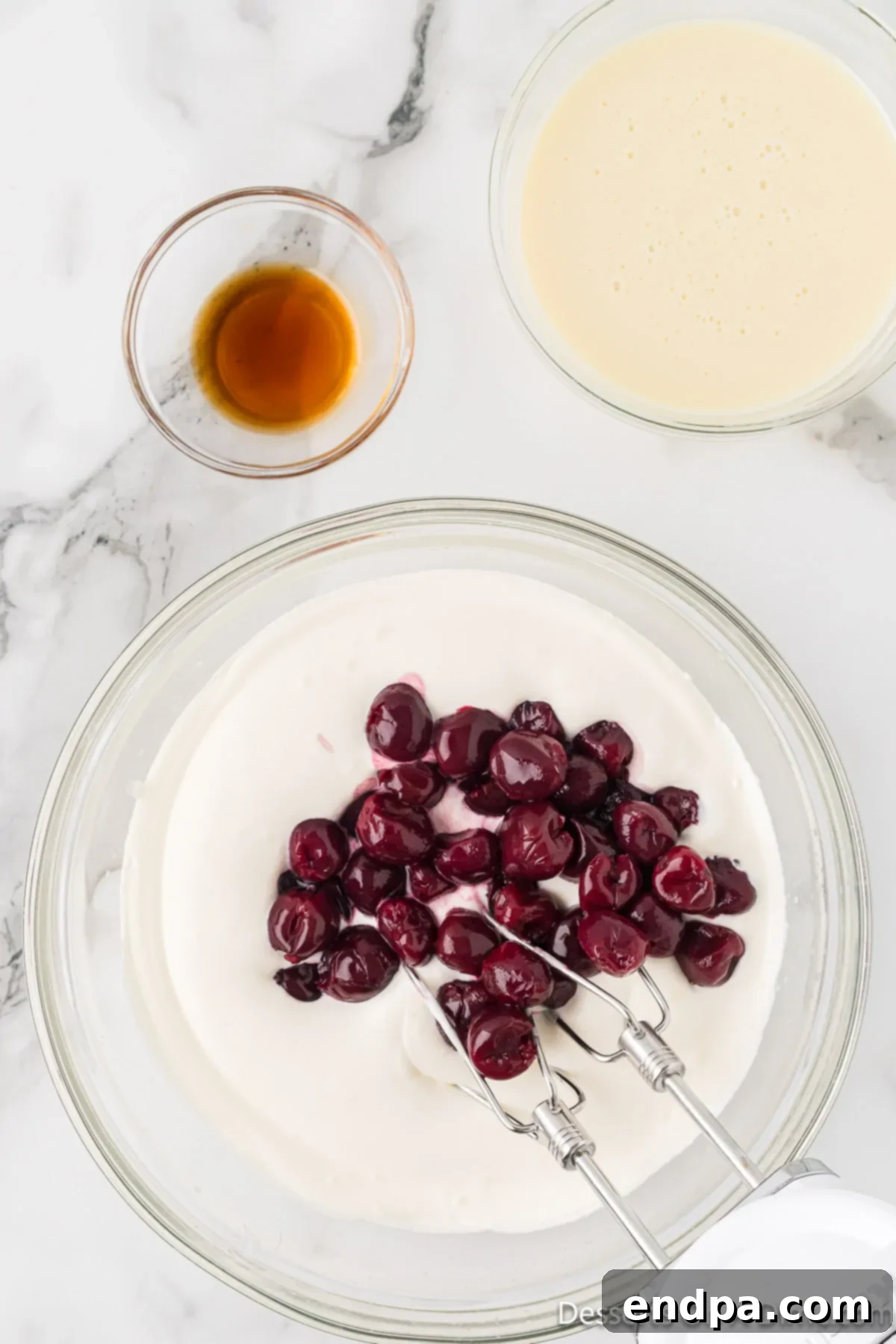 Dark Cherry Chocolate Dream Ice Cream 5 Cherries, condensed milk, and vanilla extract added to the whipped cream mixture in a bowl.