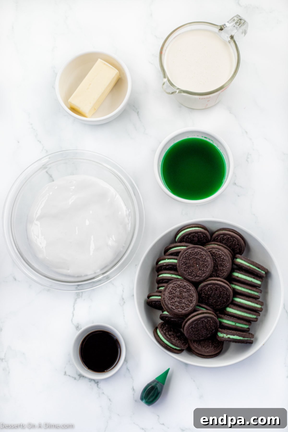 Emerald Mint Delight 3 A flat lay of ingredients for grasshopper pie including Oreo cookies, melted butter, marshmallow fluff, heavy whipping cream, green food coloring, and additional Oreos for topping.