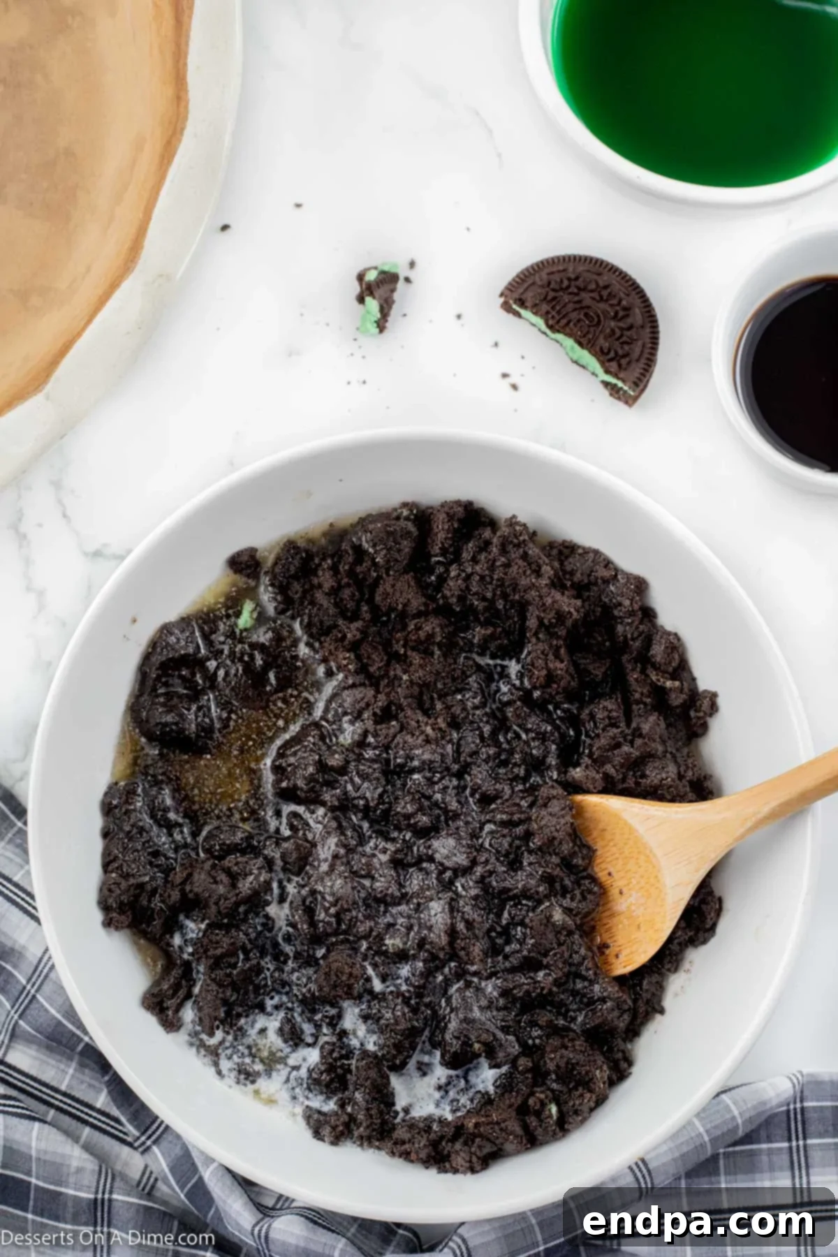 Emerald Mint Delight 4 Crushed Oreo cookies and melted butter being mixed in a bowl, ready to form the pie crust.