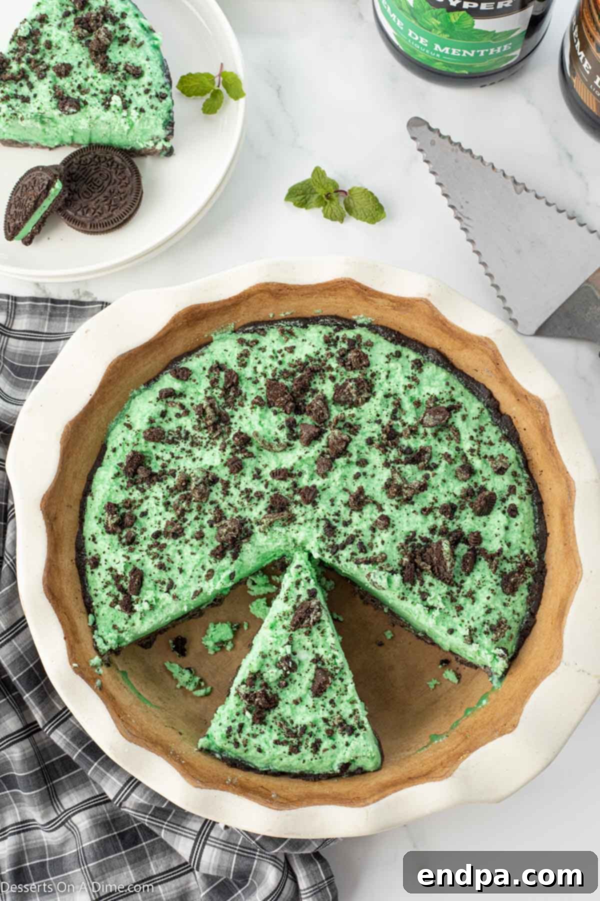 Emerald Mint Delight 10 A hand serving a slice of Grasshopper Pie, showcasing its vibrant green color and perfect consistency, ready to be enjoyed.