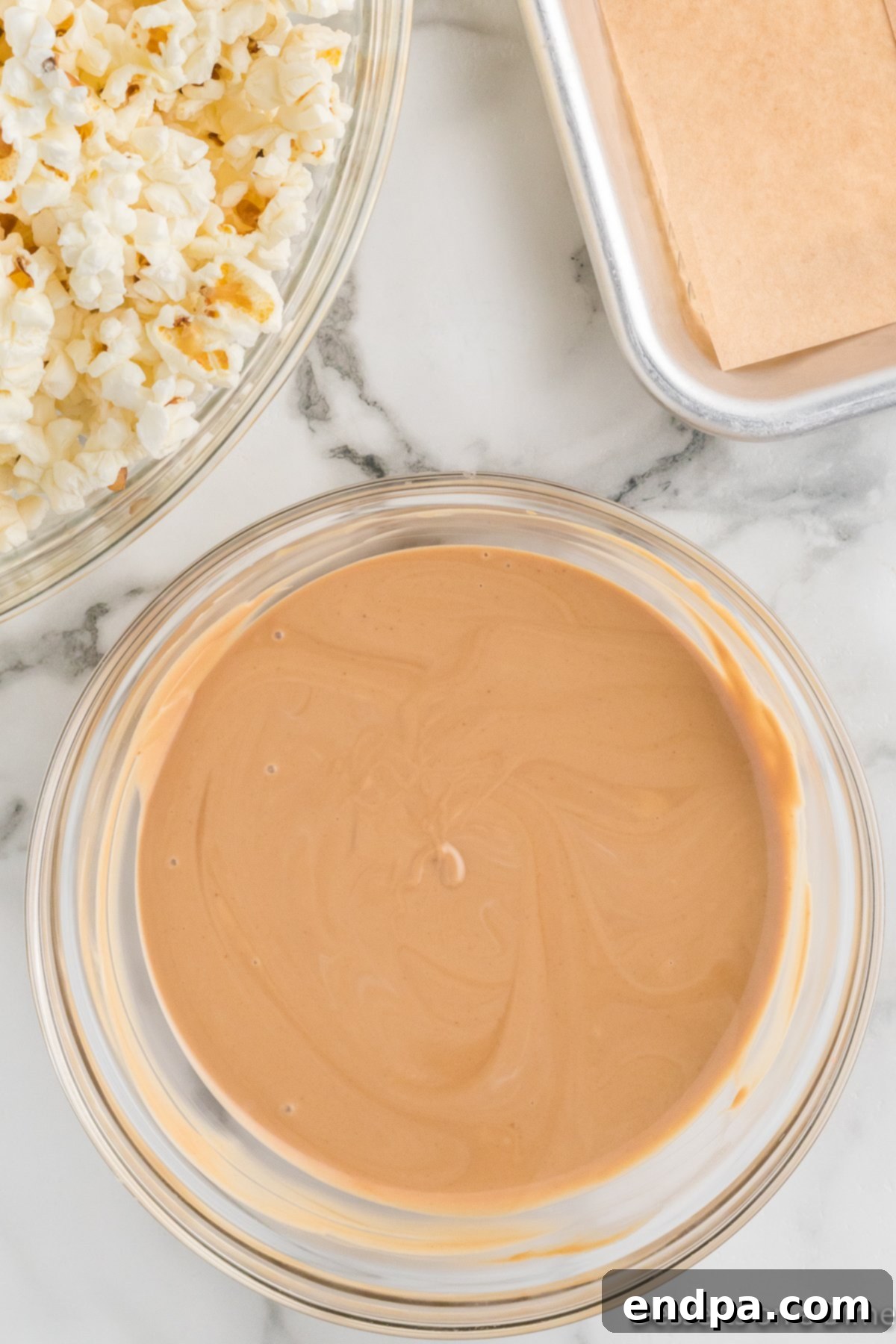 Melted cookie butter and white melting chocolate combined together in a bowl, forming a smooth, glossy mixture.