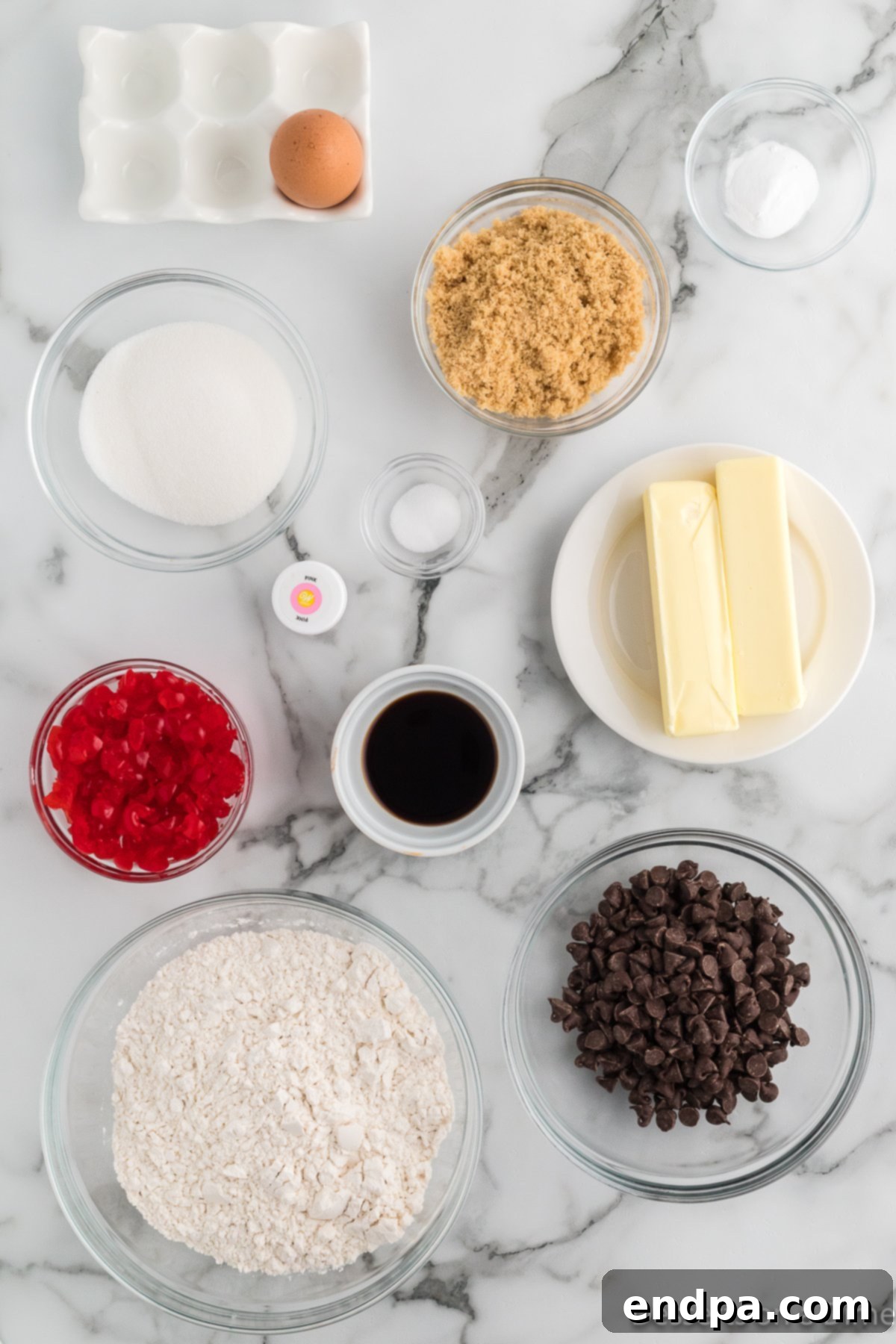 Ingredients for cherry cookies - butter, brown sugar, eggs, vanilla extract, flour, baking soda, cherries, chocolate chips, pink food coloring. 