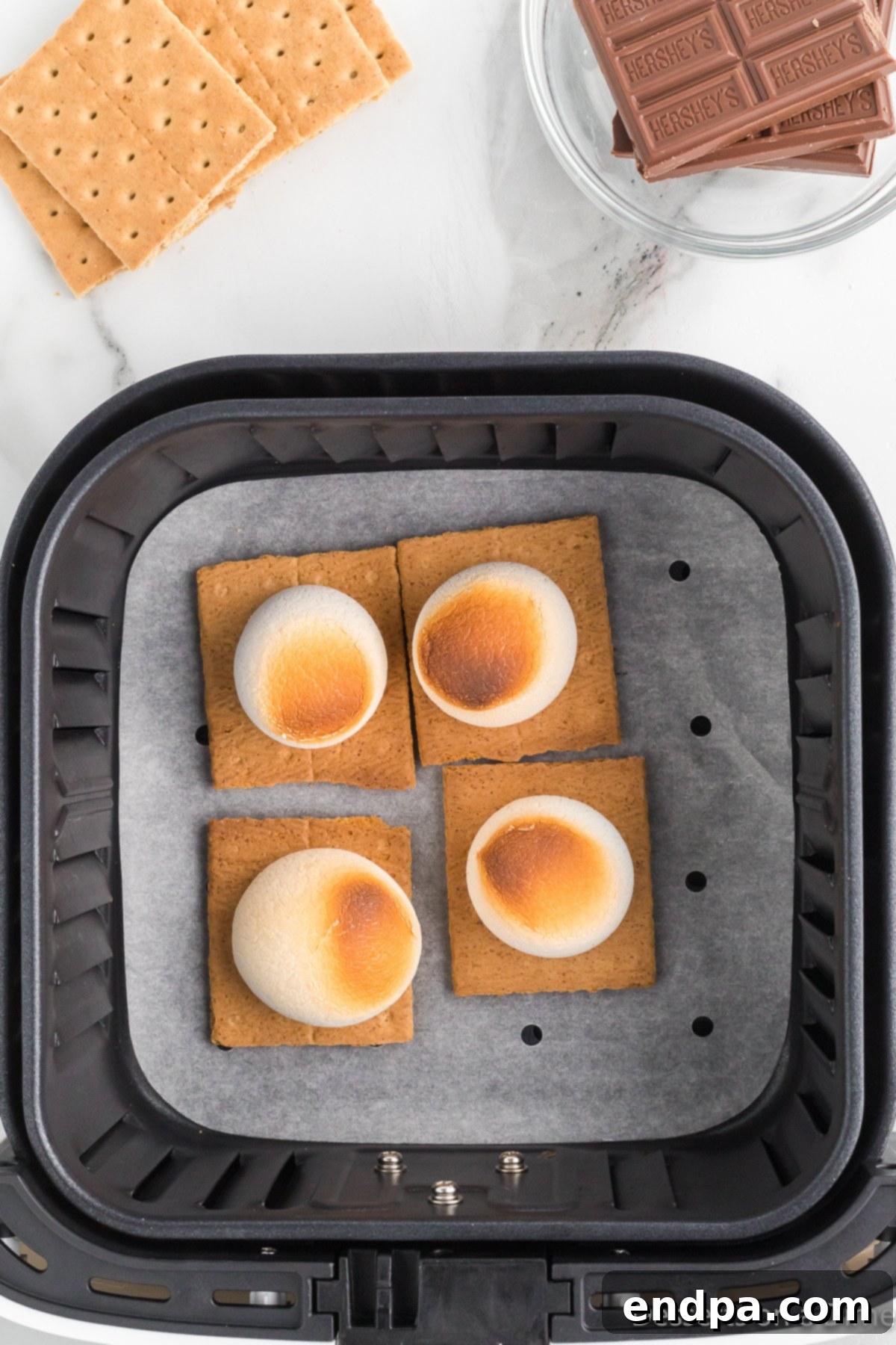 Toasted marshmallows on graham crackers in an air fryer, golden brown and slightly crispy.