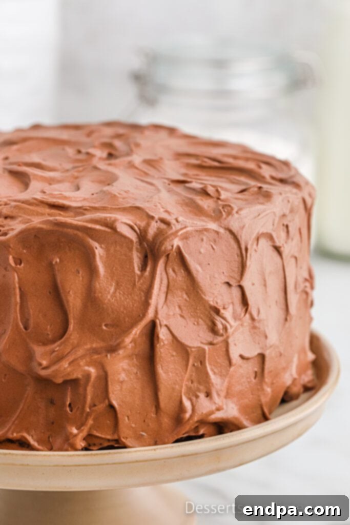 Finished chocolate mousse cake being frosted with chocolate frosting.