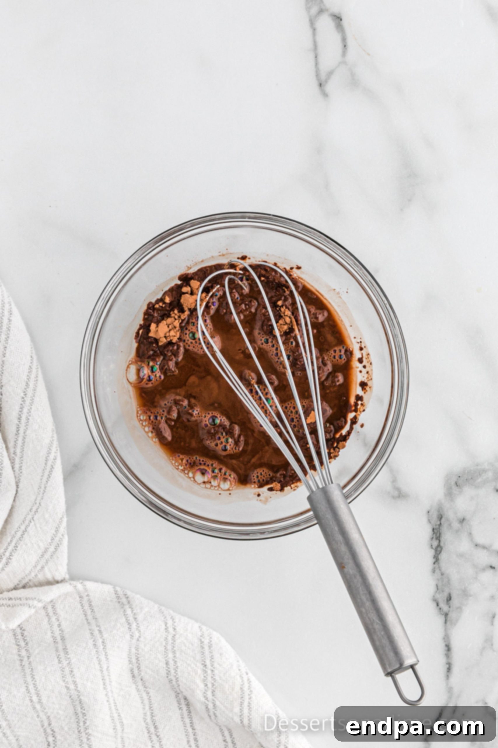 Cocoa powder and hot water being combined in a bowl to create a smooth paste.