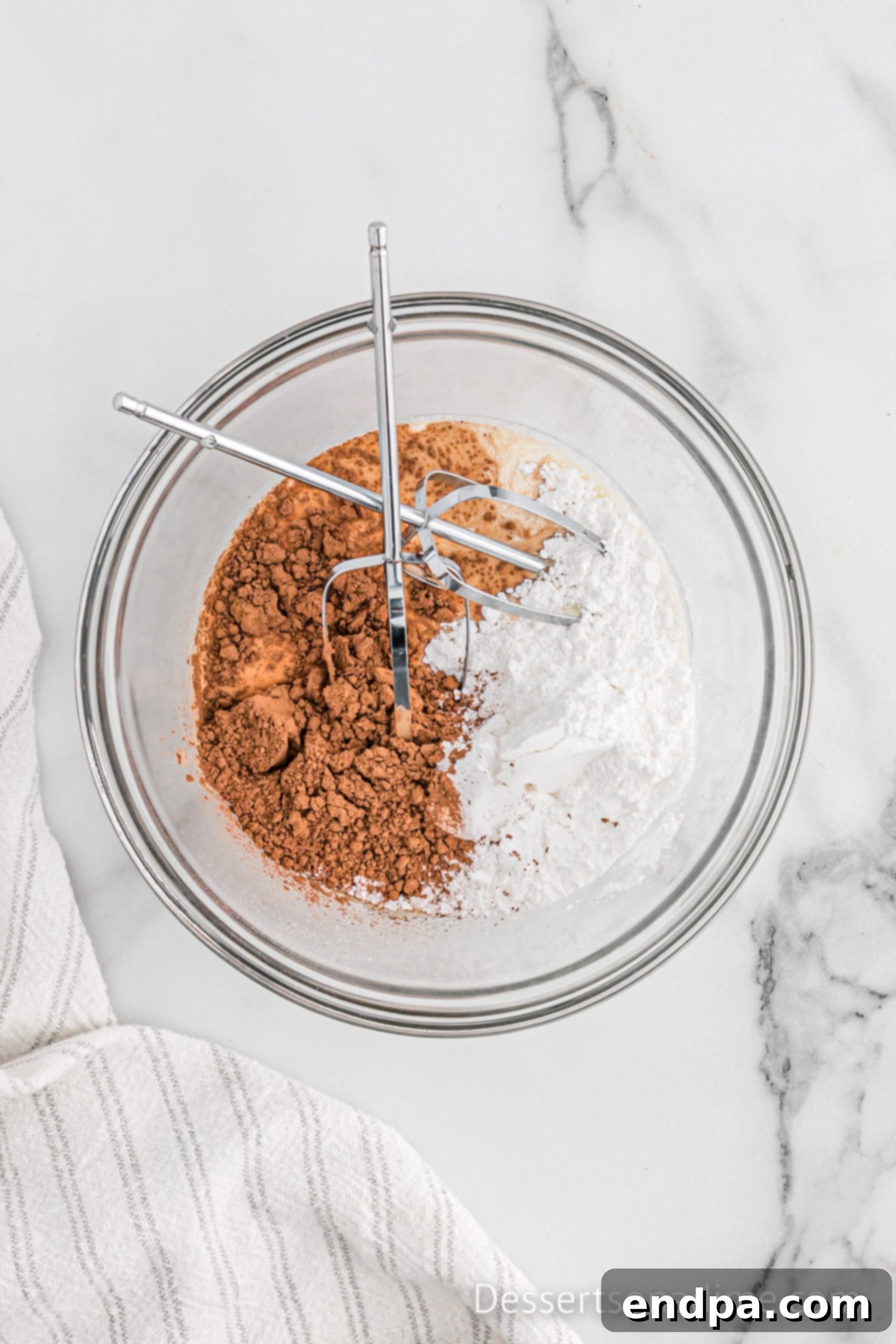 Ingredients for chocolate frosting in a bowl, ready to be beaten.