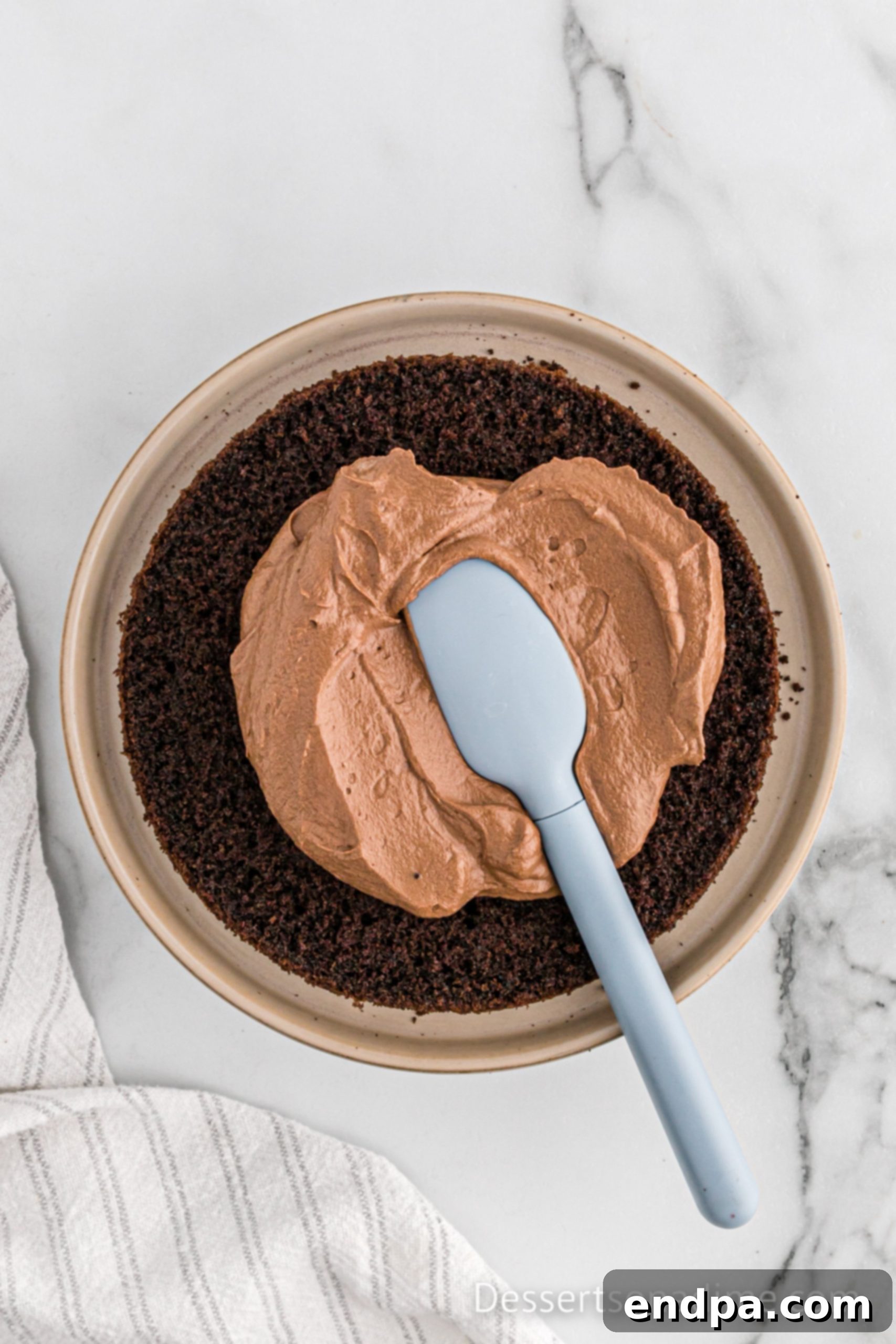 Chocolate mousse being spread evenly over a cake layer.