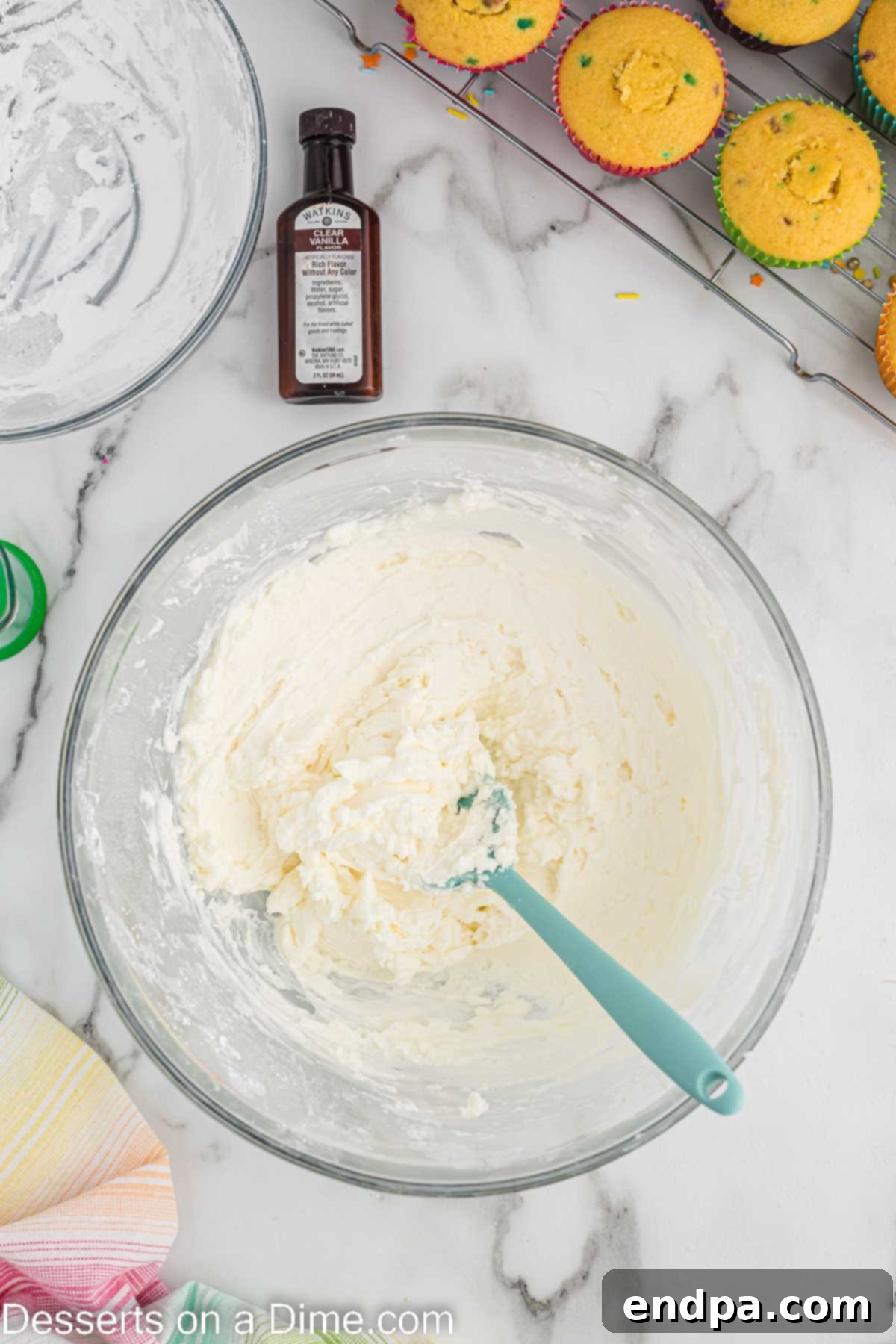 Confetti Cupcakes 8 Clear vanilla extract and milk being stirred into the frosting mixture.