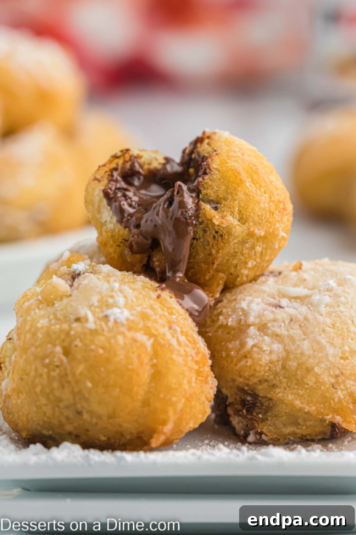 Deep fried Nutella pastries stacked on a plate, dusted with powdered sugar, ready to be served.