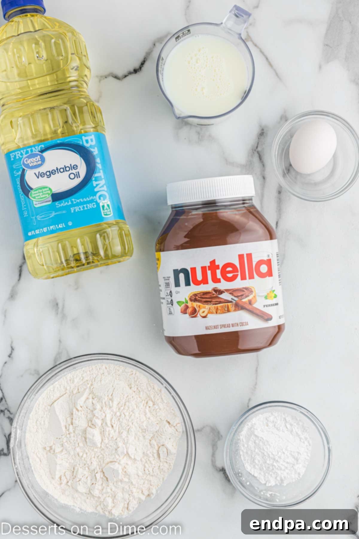 Ingredients for Deep fried Nutella laid out: a jar of Nutella, a bowl of pancake mix, a glass of milk, a bottle of vegetable oil, and a small bowl of powdered sugar.