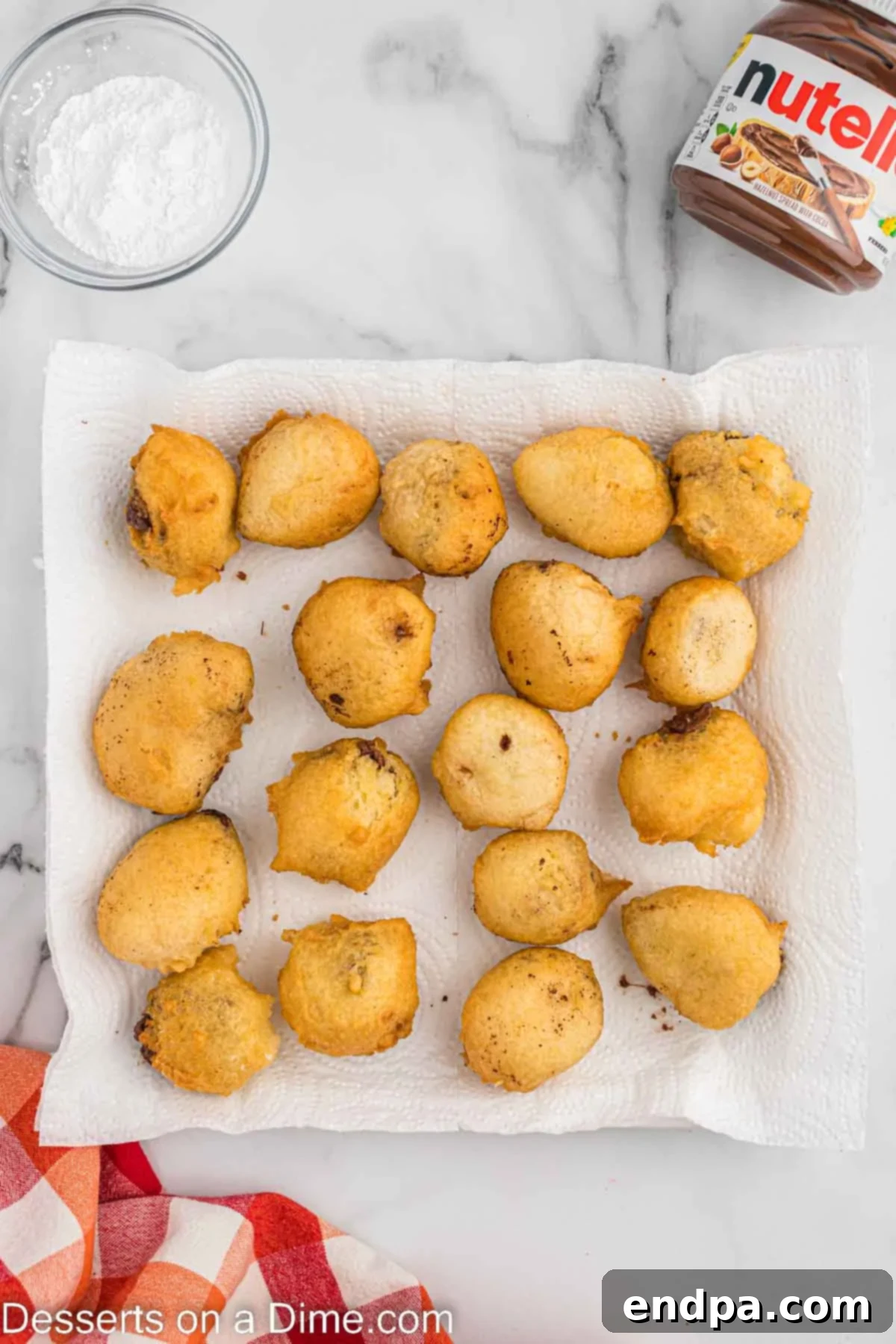 Freshly fried Nutella bites resting on a paper towel-lined plate to absorb excess oil.