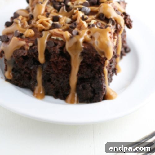 A slice of Chocolate Turtle Poke Cake, featuring layers of chocolate, caramel, and nuts.
