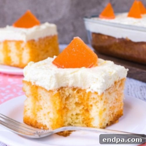 A slice of Orange Creamsicle Poke Cake with fluffy orange and white layers.