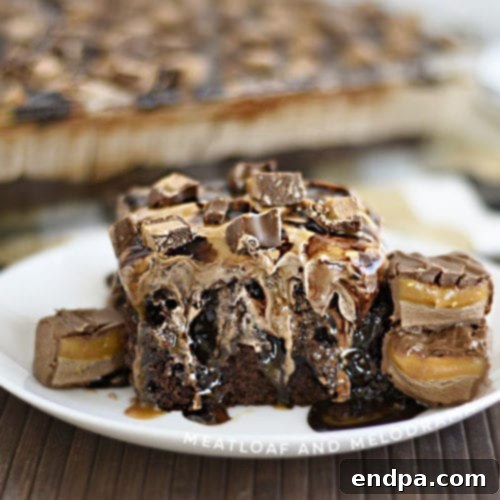 A slice of Milky Way Poke Cake, adorned with chocolate, caramel, and pieces of Milky Way bars.