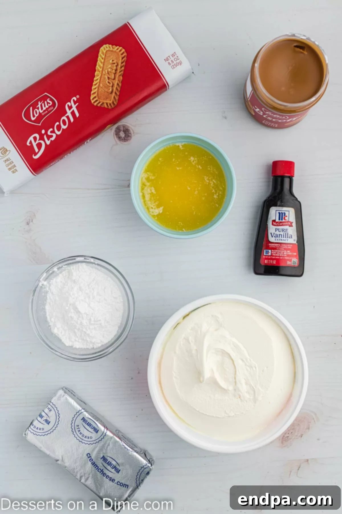 Decadent Cookie Butter Cheesecake 3 Ingredients for Cookie Butter Cheesecake - Biscoff cookies, butter, cream cheese, powdered sugar, vanilla, cookie butter, whipped cream, arranged on a rustic wooden surface.